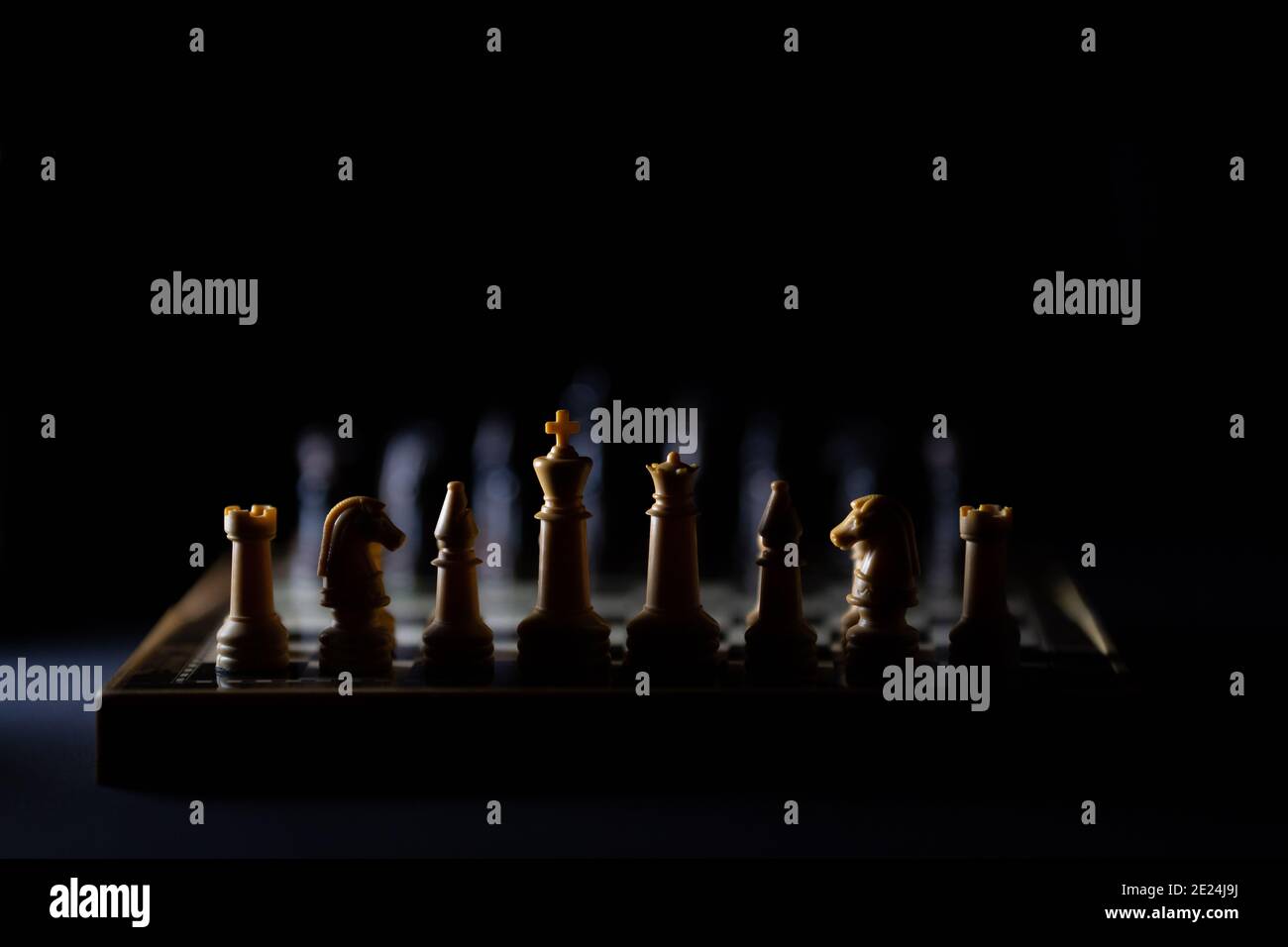 Pezzi di scacchi su una scacchiera in uno stile scuro con una luce bianca. Messa a fuoco selettiva Foto Stock