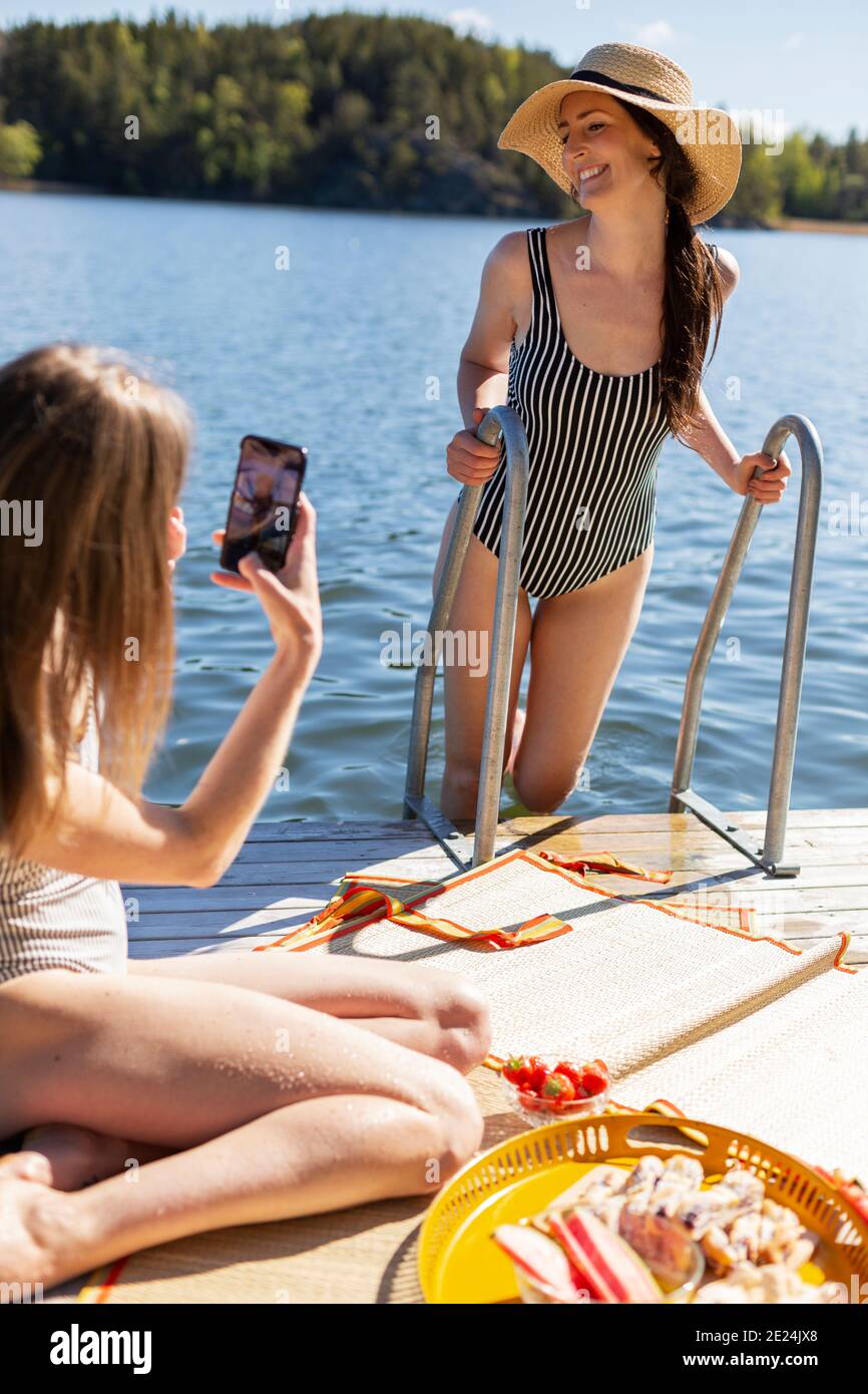 Felici le amiche che si rilassano sul molo Foto Stock