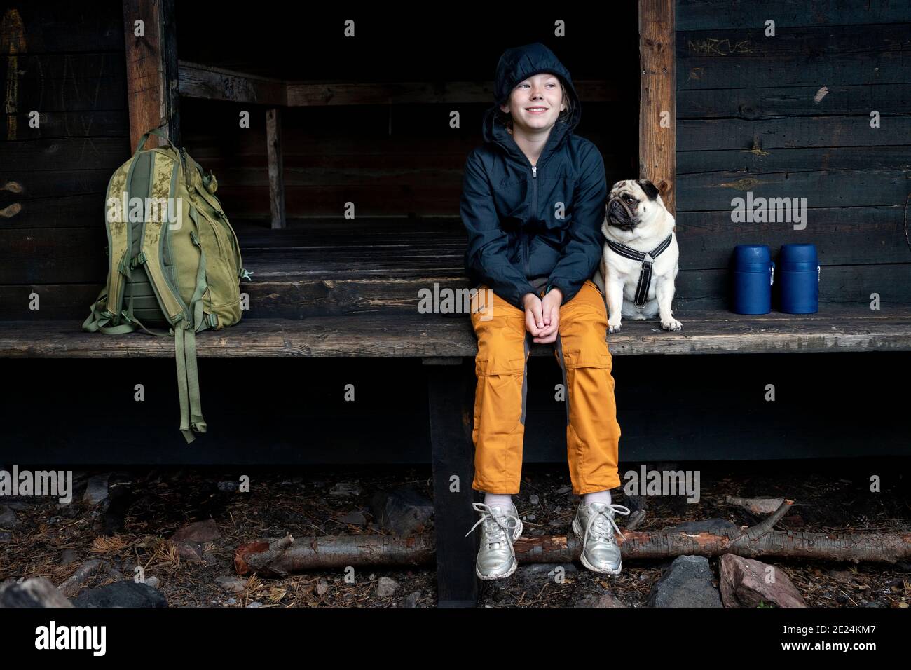 Ragazza con pug seduta da edificio in legno Foto Stock
