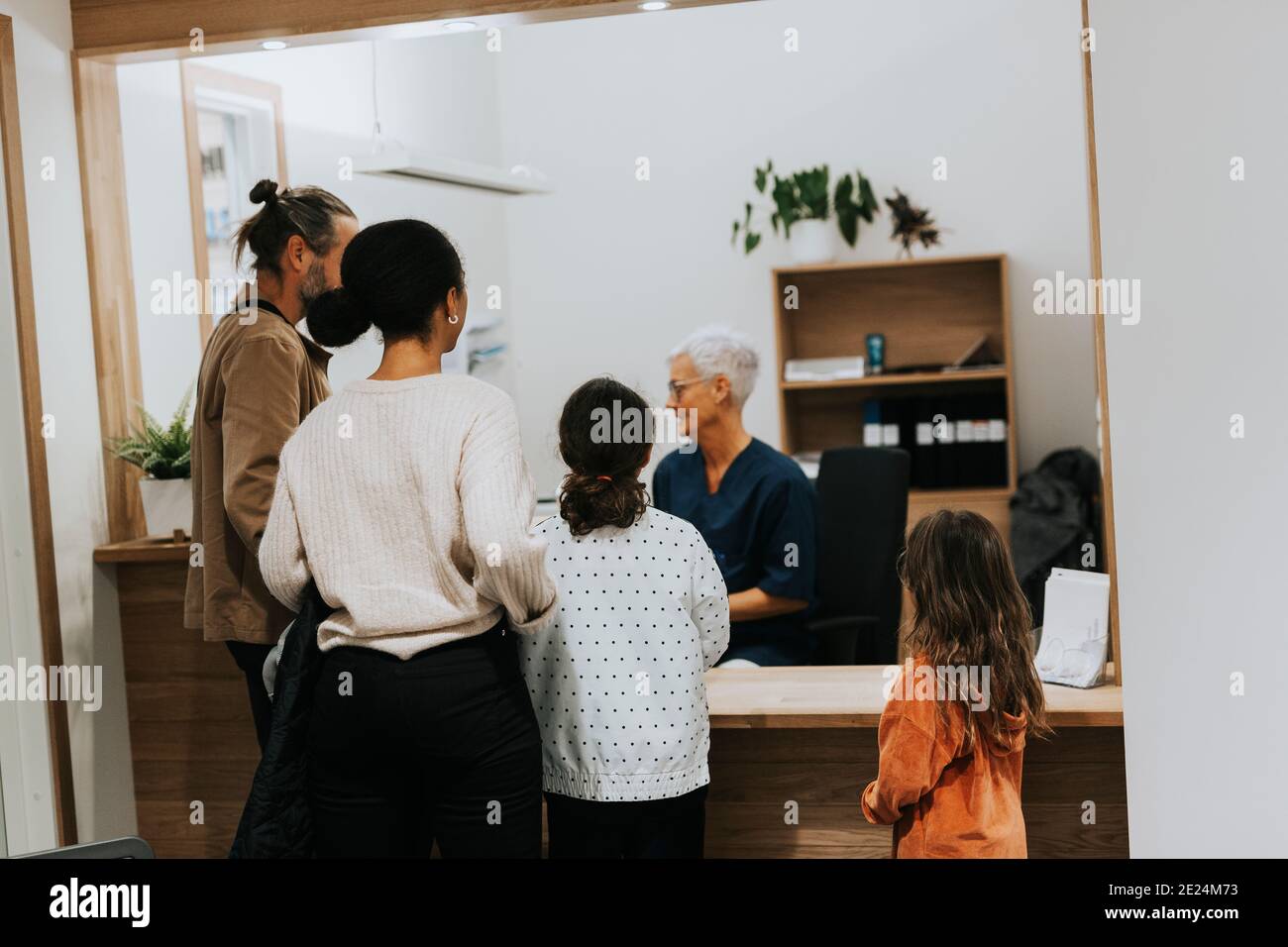 La famiglia parla con il receptionist in chirurgia Foto Stock