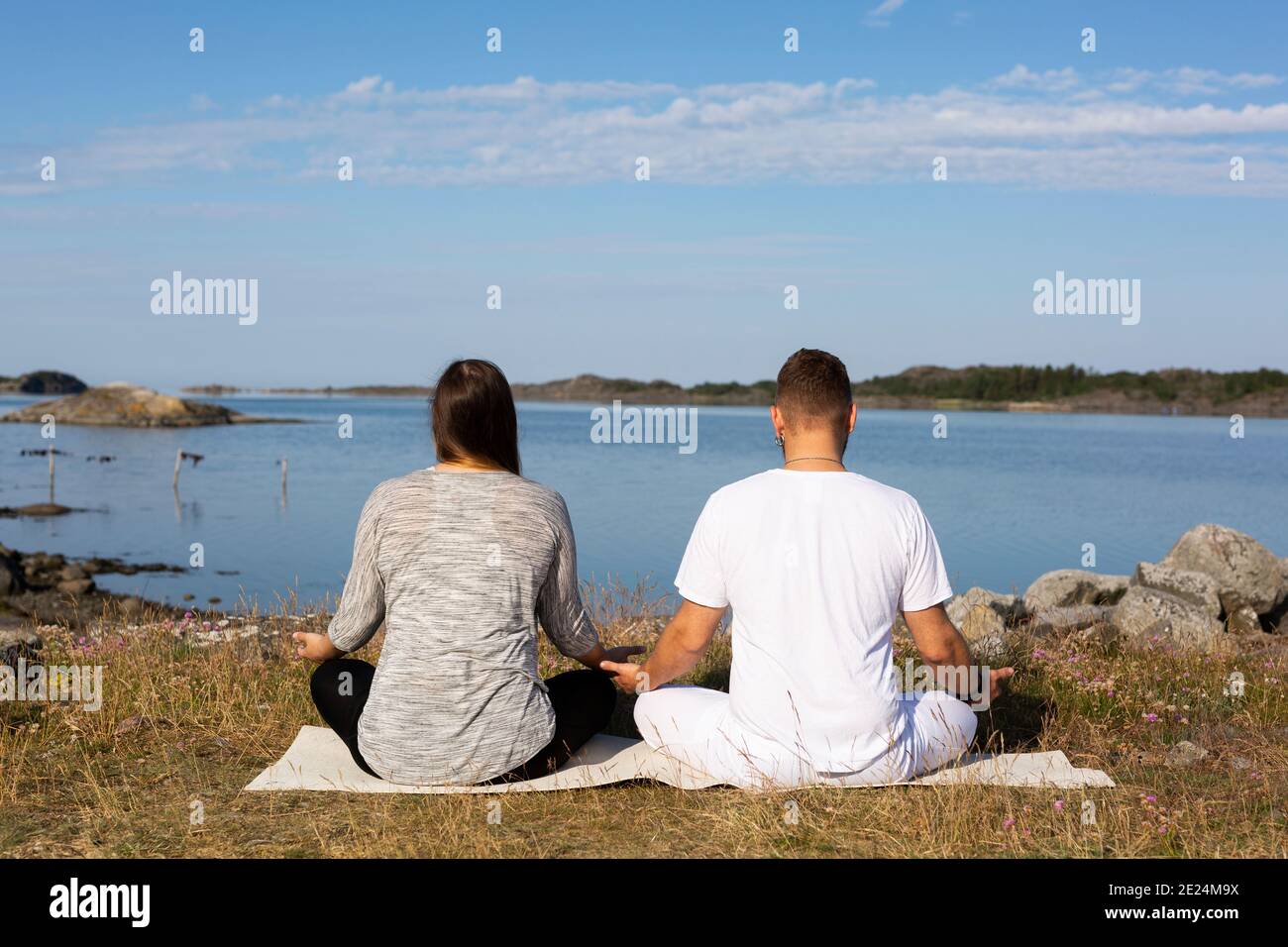 Uomo e donna che meditano in mare Foto Stock