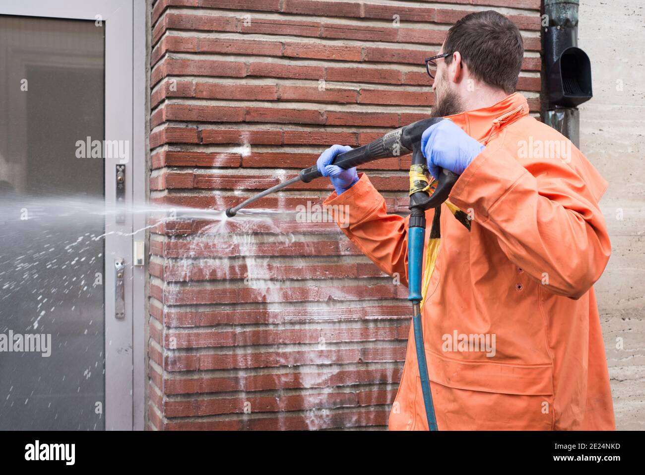 Uomo che pulisce i graffiti dalla parete Foto Stock