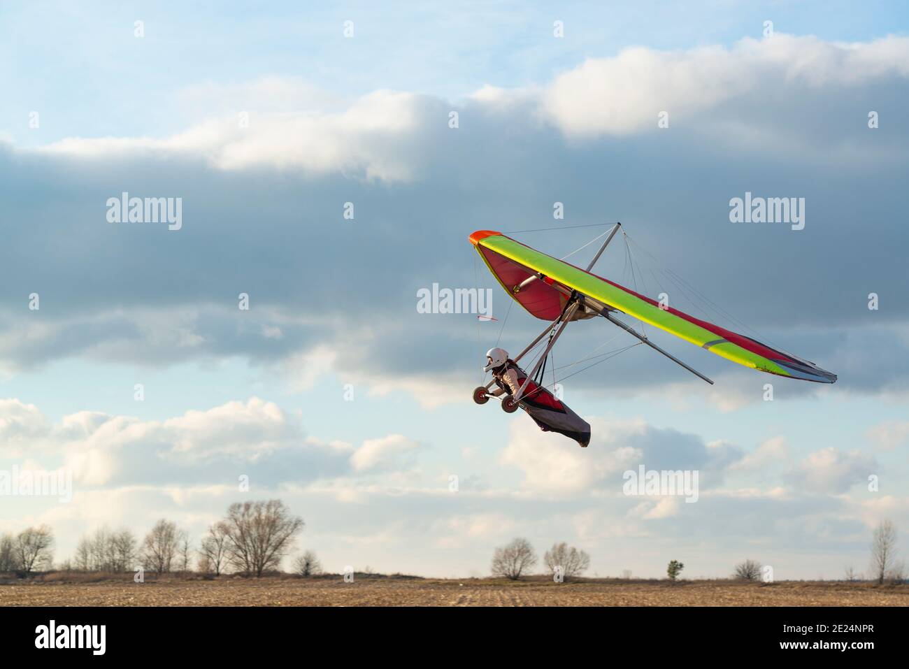 Coraggiosa ragazza imparare a volare sulla colorata ala deltaplano. Attività sportive estreme con splendido cielo al tramonto sullo sfondo. Deltaplano Foto Stock