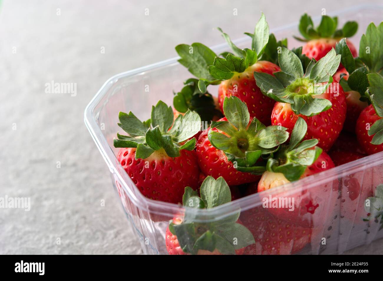 Fragole in confezione di plastica su fondo di pietra grigio Foto Stock