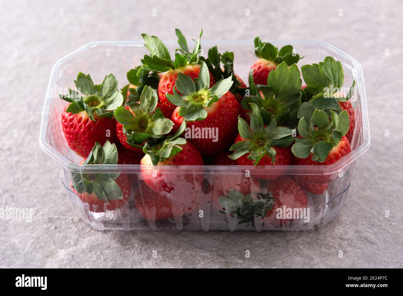 Fragole in confezione di plastica su fondo di pietra grigio Foto Stock