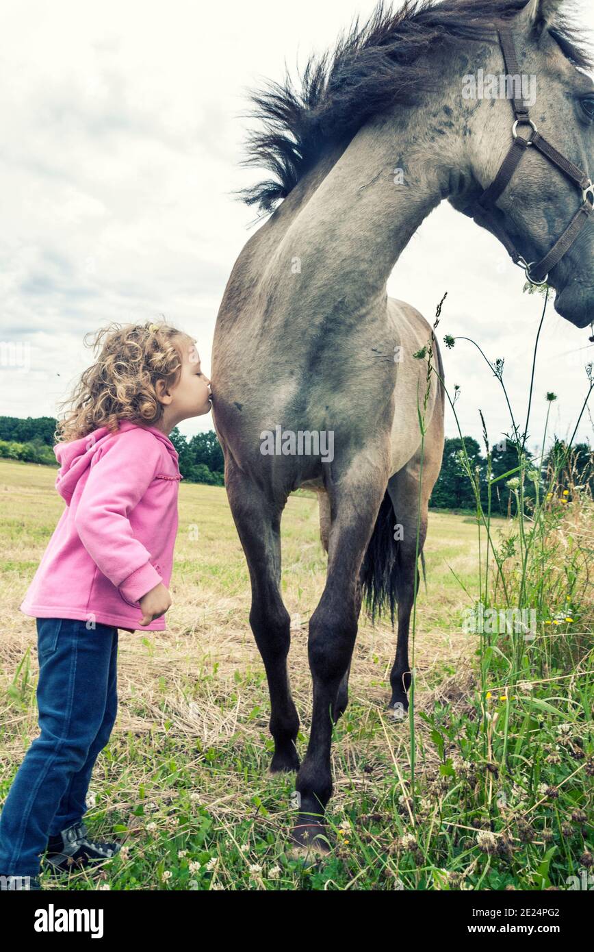 Ragazza in piedi in un campo baciando un cavallo, Polonia Foto Stock