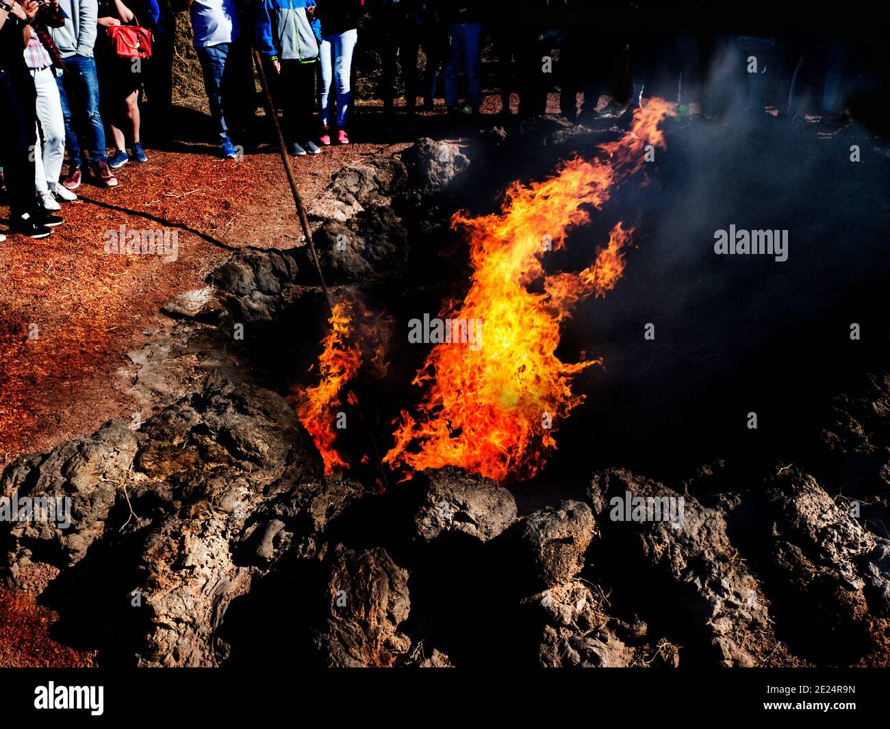 Gruppo di persone in piedi intorno a un incendio in un cratere vulcanico, Lanzarote, Isole Canarie, Spagna Foto Stock
