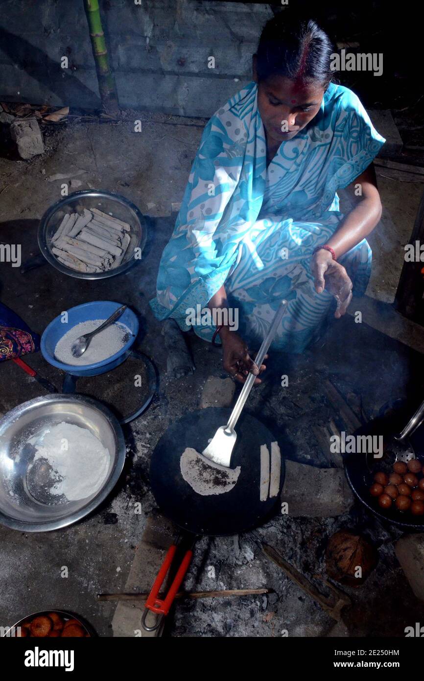 Nagaon, Assam, India - 12 gennaio 2021: Una donna che prepara i tradizionali pithas teel per Magh Bihu nel villaggio di Kachamari nel distretto di Nagaon ad Assam, India. Magh Bihu, in particolare, è una celebrazione della generosità della messe della natura e un’ode alla continuità dell’esistenza. È naturale che Magh Bihu o Bhogali Bihu, come viene comunemente chiamato, sia una ricca celebrazione del ricco bacino di cibo tradizionale e di preparazioni gastronomiche dello Stato. Credit: Dita TALUKDAR/Alamy Live News Foto Stock