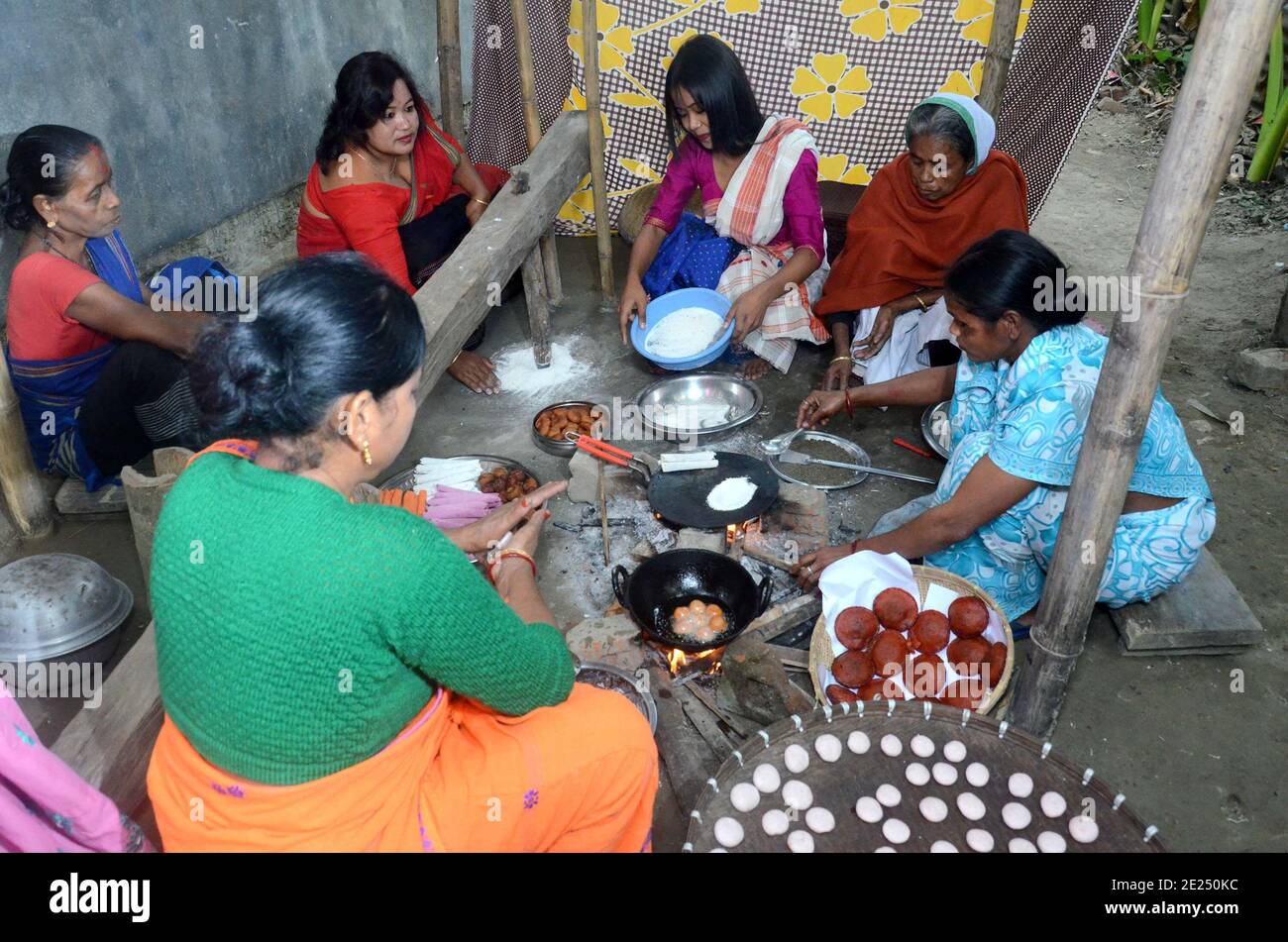 Nagaon, Assam, India - 12 Gennaio 2021:le donne del villaggio sono impegnate nella preparazione di pithas teel tradizionali e altri oggetti per Magh Bihu nel villaggio di Kachamari nel distretto di Nagaon di Assam, India. Magh Bihu, in particolare, è una celebrazione della generosità della messe della natura e un’ode alla continuità dell’esistenza. È naturale che Magh Bihu o Bhogali Bihu, come viene comunemente chiamato, siano una ricca celebrazione del ricco bacino di cibo tradizionale e di preparazioni gastronomiche dello Stato. Credit: Dita TALUKDAR/Alamy Live News Foto Stock