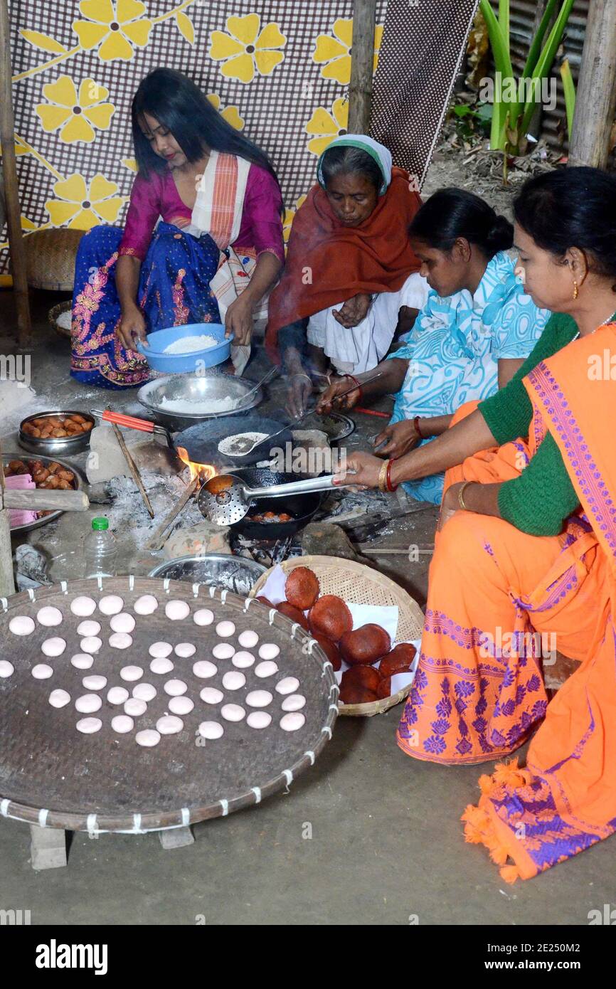 Nagaon, Assam, India - 12 Gennaio 2021:le donne del villaggio sono impegnate nella preparazione di pithas teel tradizionali e altri oggetti per Magh Bihu nel villaggio di Kachamari nel distretto di Nagaon di Assam, India. Magh Bihu, in particolare, è una celebrazione della generosità della messe della natura e un’ode alla continuità dell’esistenza. È naturale che Magh Bihu o Bhogali Bihu, come viene comunemente chiamato, sia una ricca celebrazione del ricco bacino di cibo tradizionale e di preparazioni gastronomiche dello Stato. Credit: Dita TALUKDAR/Alamy Live News Foto Stock
