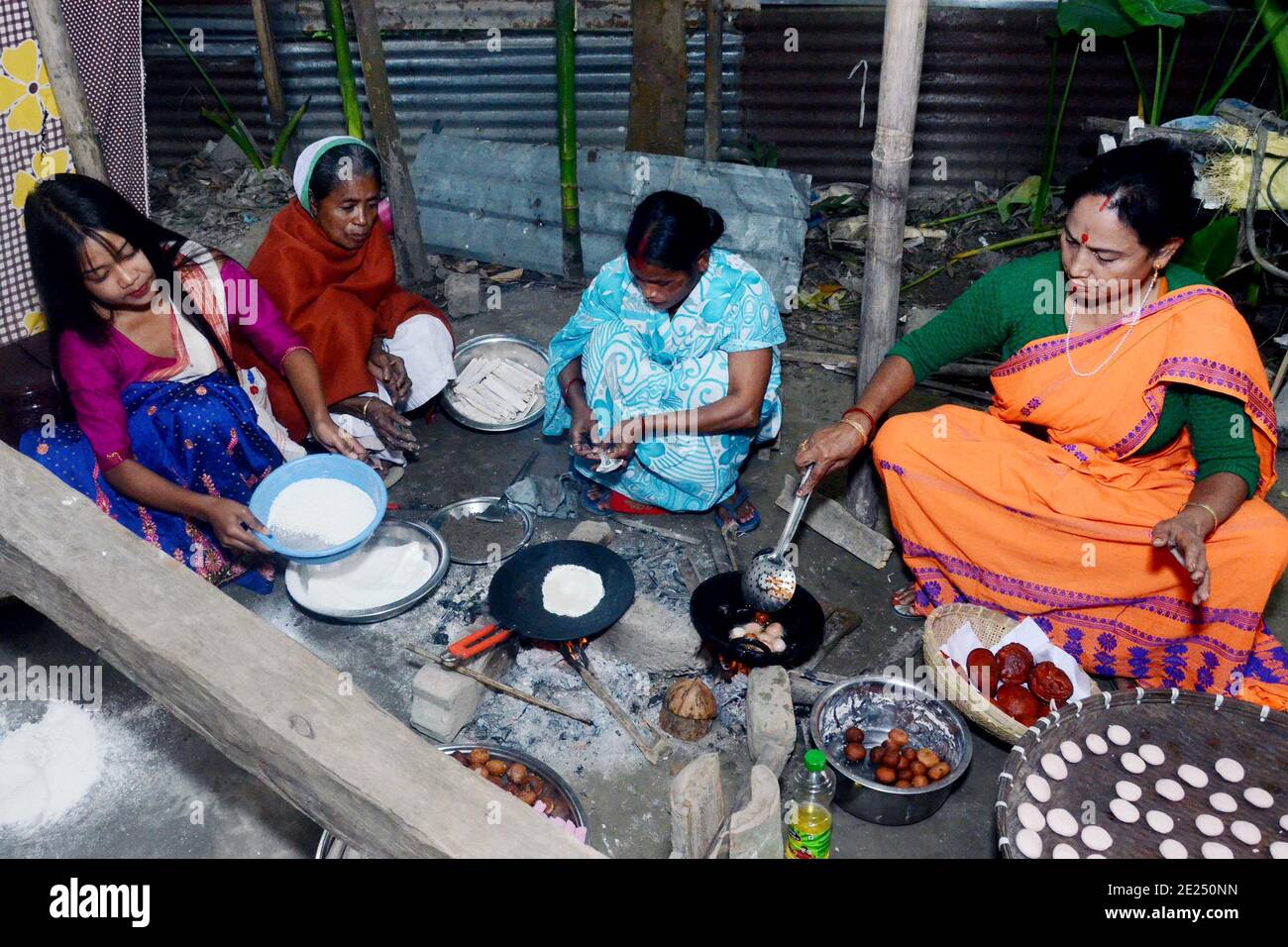 Nagaon, Assam, India - 12 gennaio 2021: Le donne del villaggio sono impegnate nella preparazione di pithas teel tradizionali e altri oggetti per Magh Bihu nel villaggio di Kachamari nel distretto di Nagaon di Assam, India. Magh Bihu, in particolare, è una celebrazione della generosità della messe della natura e un’ode alla continuità dell’esistenza. È naturale che Magh Bihu o Bhogali Bihu, come viene comunemente chiamato, sia una ricca celebrazione del ricco bacino di cibo tradizionale e di preparazioni gastronomiche dello Stato. Credit: Dita TALUKDAR/Alamy Live News. Foto Stock