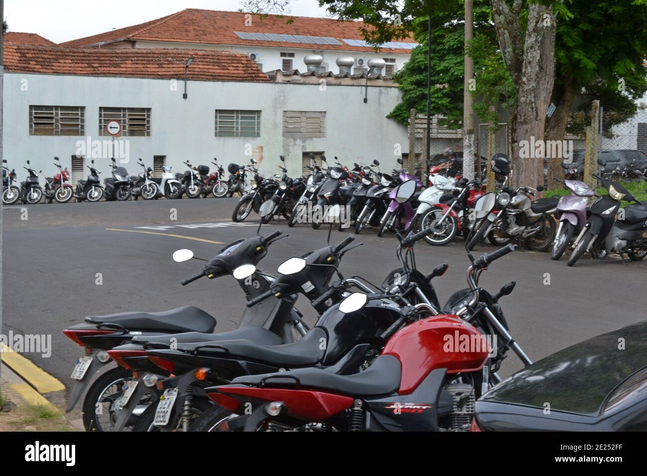 Motociclette parcheggiate sulla strada accanto all'ospedale, con diverse moto tra loro di vari tipi, colori e modelli in una città in t Foto Stock