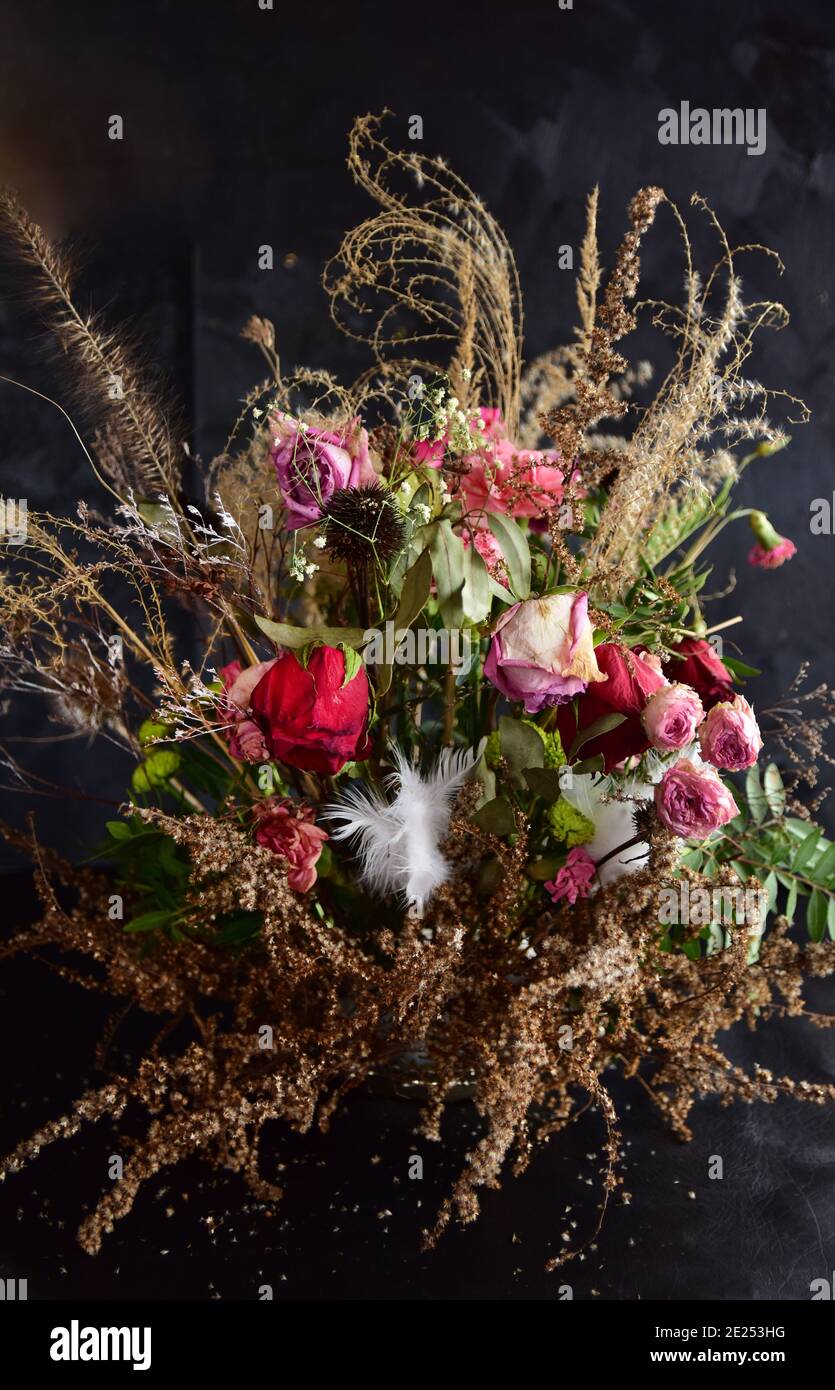 Floristry, un bel bouquet femminile naturale ornato di rose, garofani, erbe e ramoscelli verdi su sfondo nero. Foto Stock