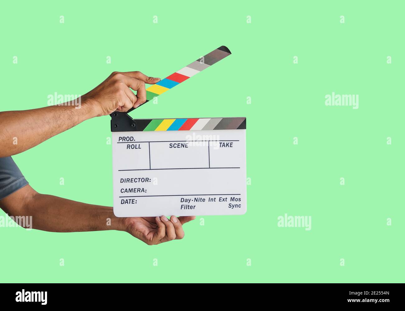 Mano che tiene un'ardesia di clapboard di pellicola o ardesia di film isolata su sfondo verde, con tracciato di clipping. Foto Stock