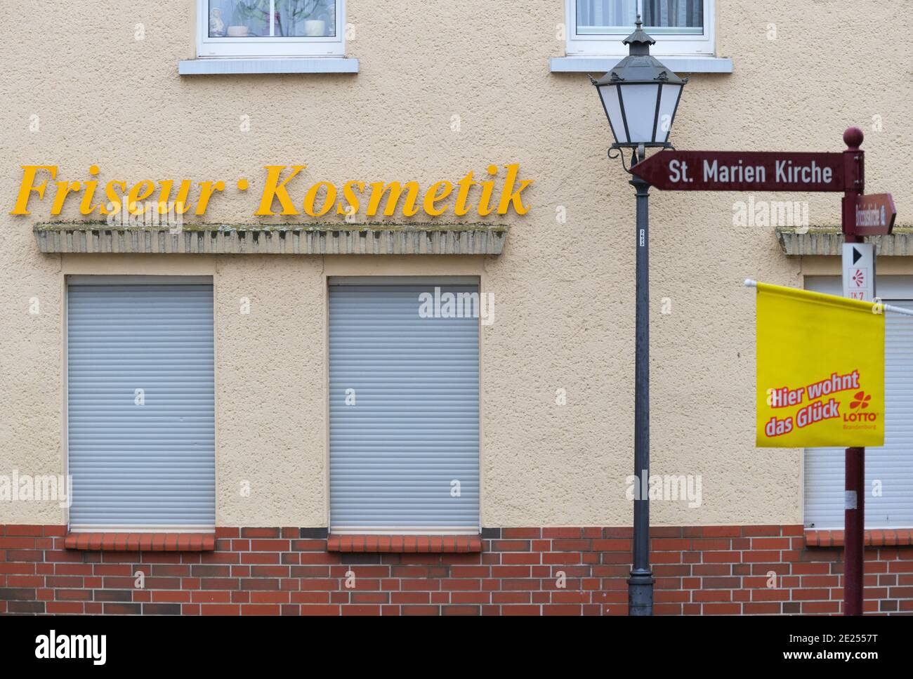 Bad Belzig, Germania. 12 gennaio 2021. Le persiane di fronte alle finestre di un parrucchiere e di un salone di bellezza nel centro della città sono abbassate. Il banner di fronte all'ingresso di una lotteria dice 'Lotto. La fortuna vive qui'. Credit: Soeren Stache/dpa-Zentralbild/ZB/dpa/Alamy Live News Foto Stock