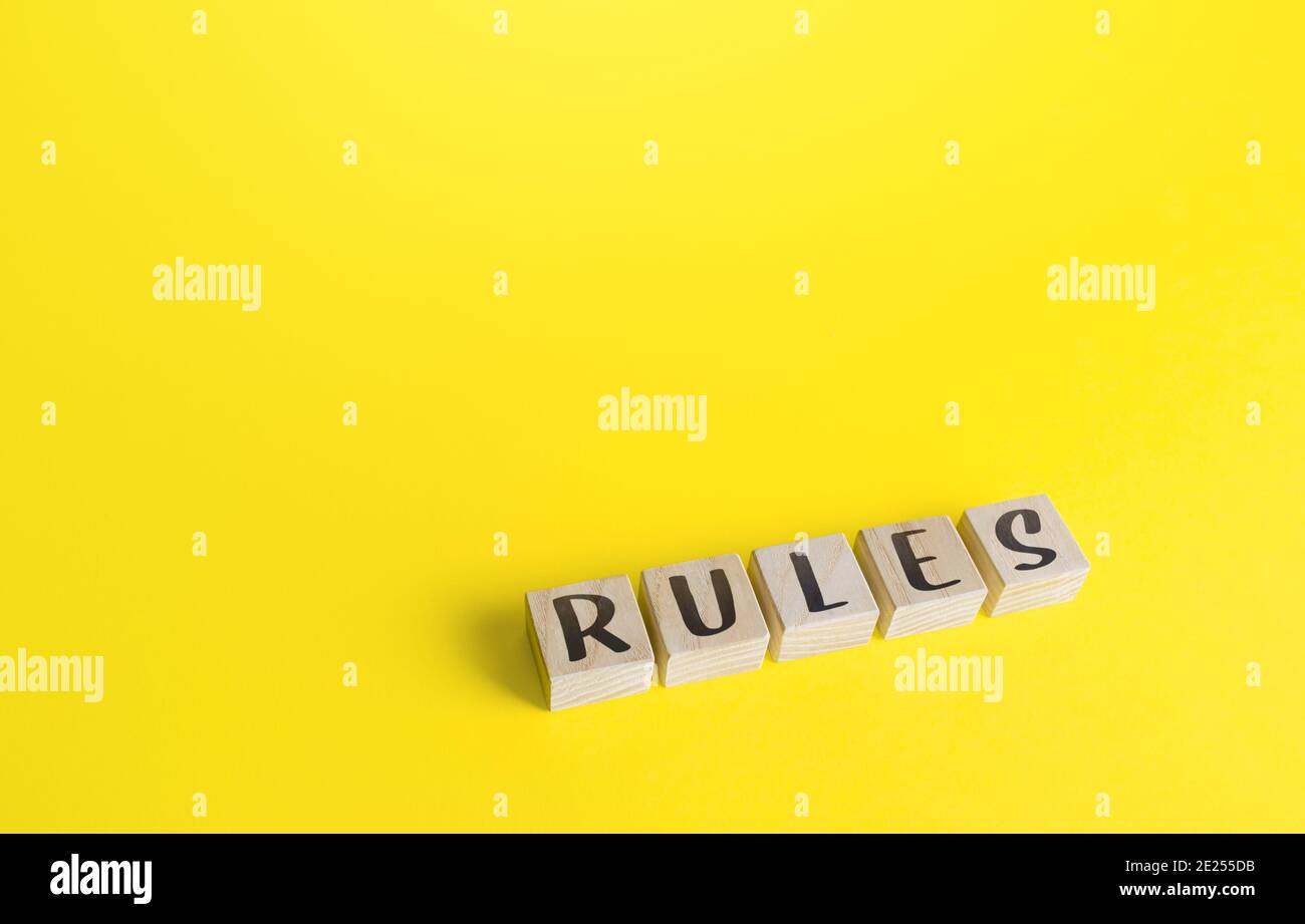 Blocchi con la parola regole su sfondo giallo. Leggi e norme di etica comunitaria. Condizioni del contratto e obblighi delle parti. Controllare un Foto Stock