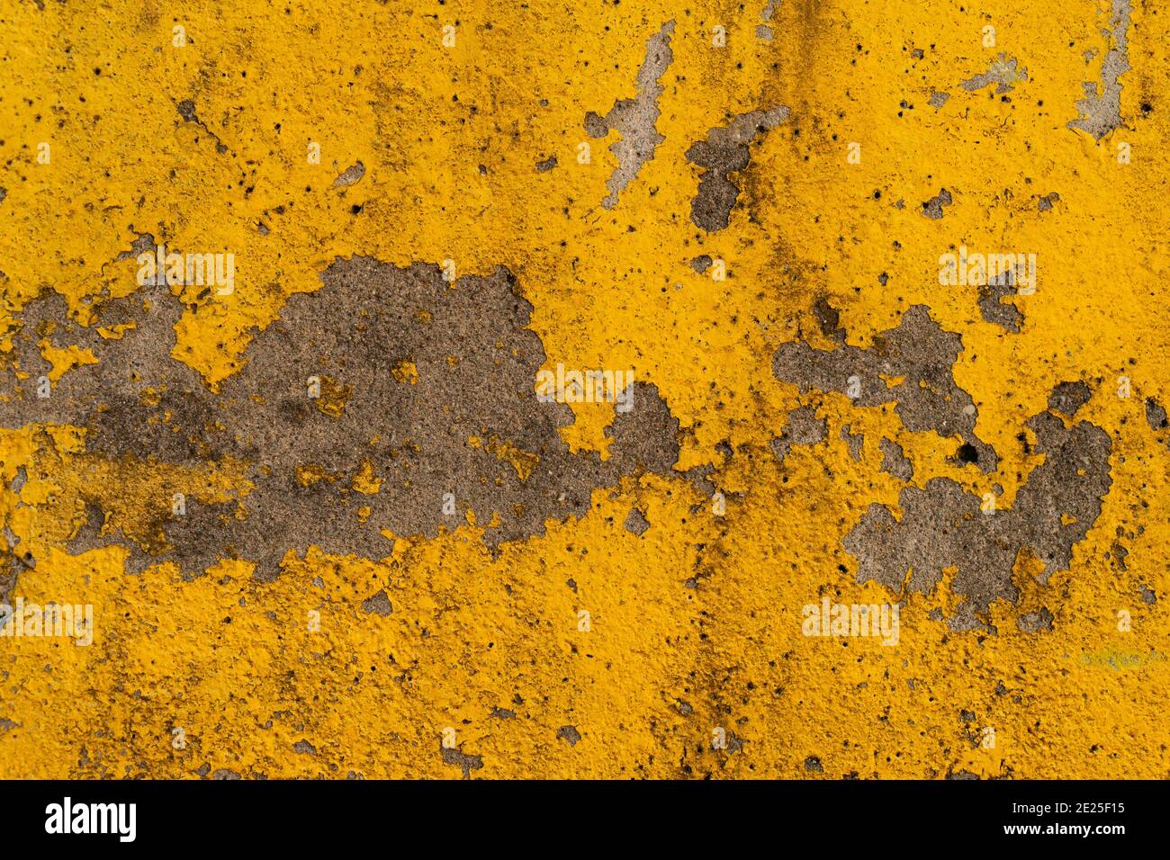 Vista ravvicinata della vernice giallo brillante che si stacca e si indossa su una superficie di cemento. Foto Stock