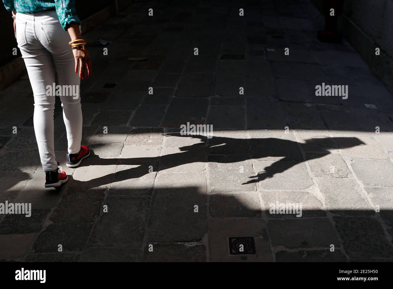 Silhouette e ombra di una donna che cammina uomo su una strada stretta. Foto Stock