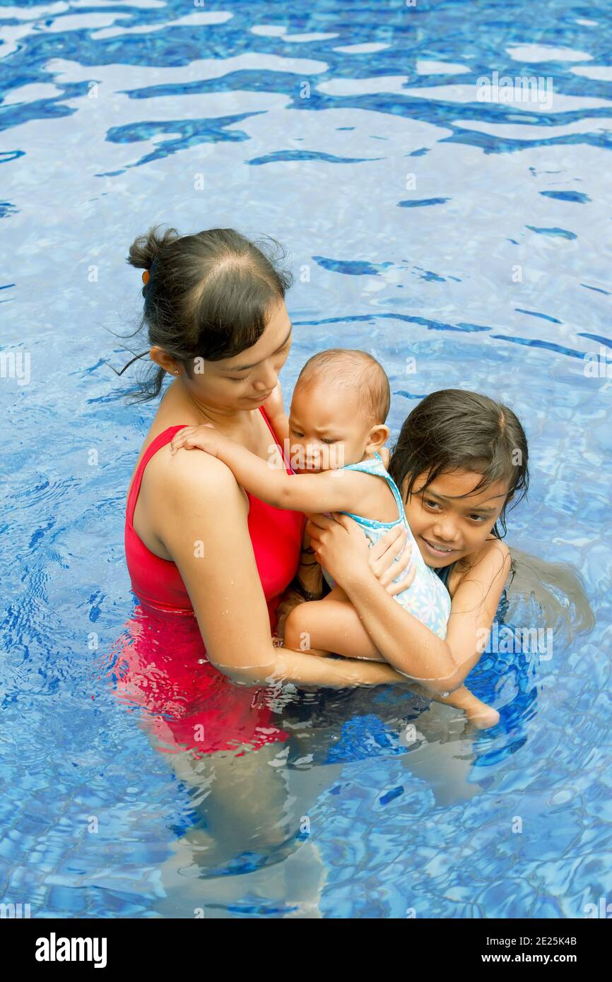 Famiglia asiatica attiva di madre, bambino e bambino che nuotano insieme Foto Stock