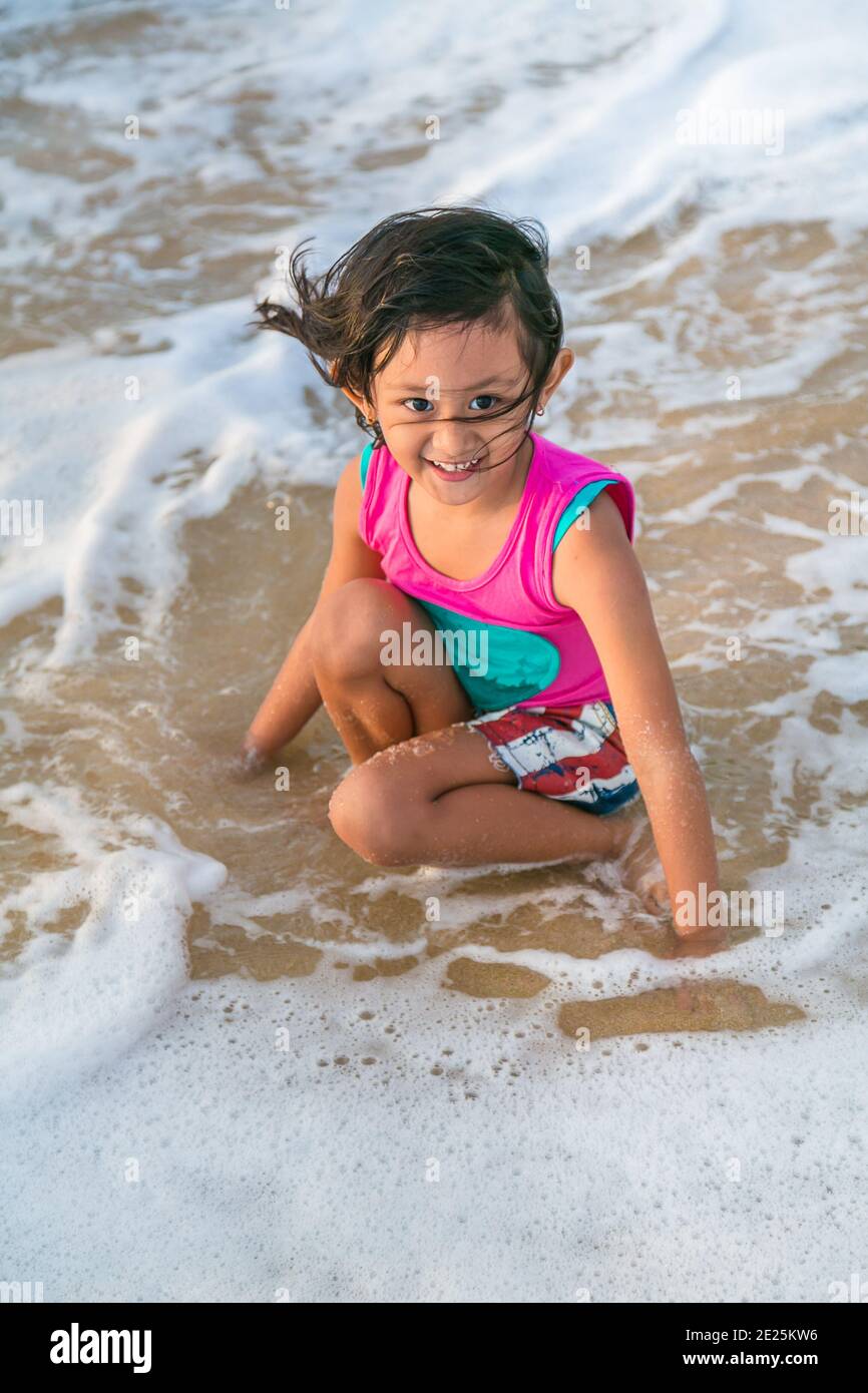 Asian Little Girl Godetevi giocando a Sea Shore Foto Stock