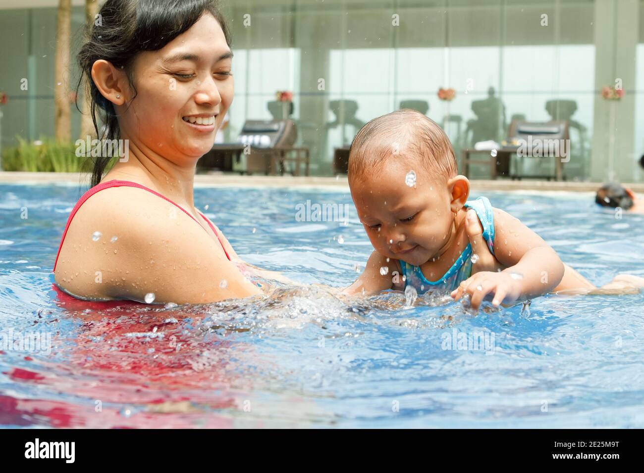 Felice madre etnica asiatica insegnano al bambino a nuotare Foto Stock