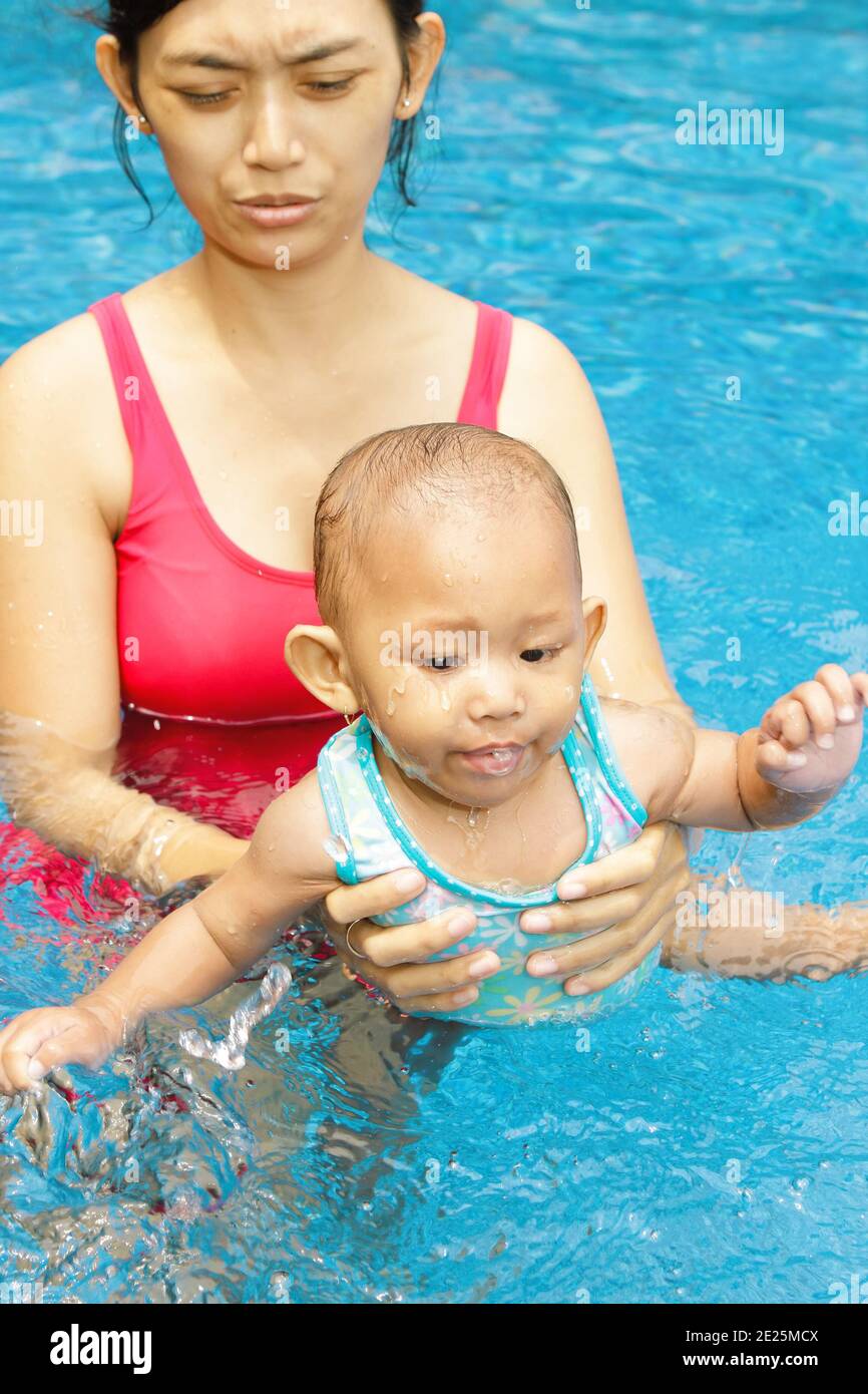 Madre etnica asiatica insegnano alla bambina a nuotare Foto Stock