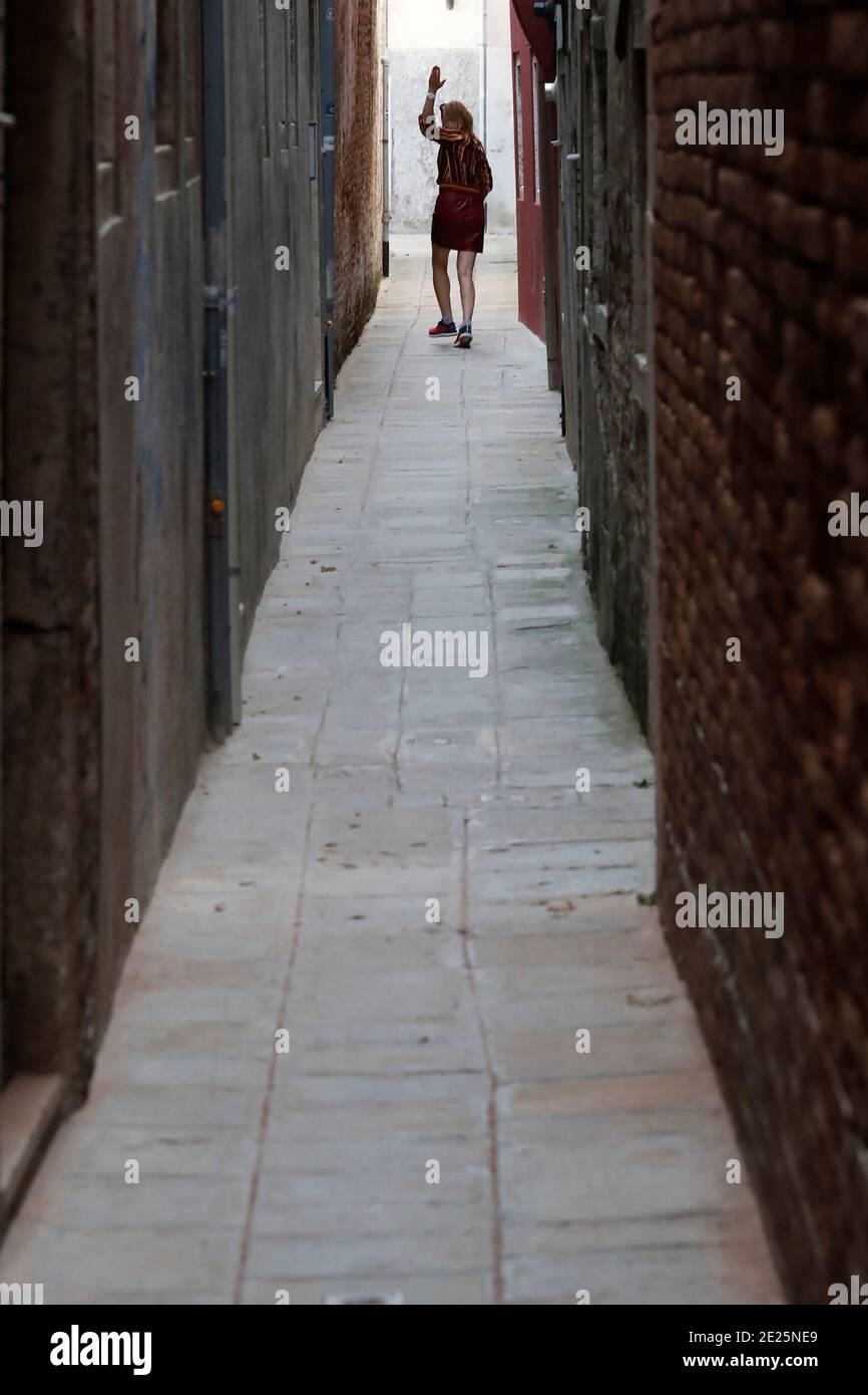 Silhouette di una donna che cammina uomo su una strada stretta. Foto Stock