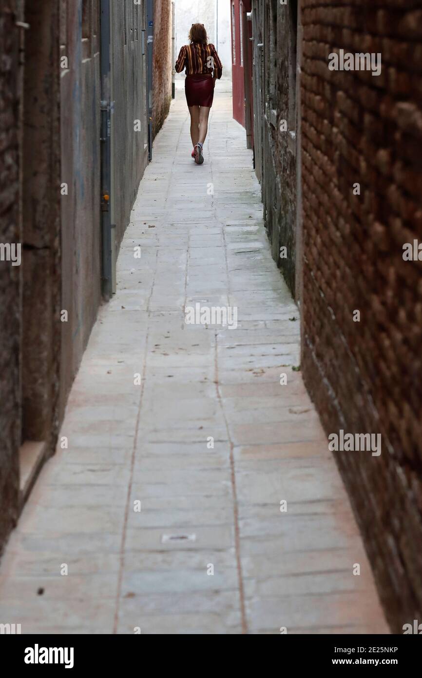 Silhouette di una donna che cammina uomo su una strada stretta. Foto Stock
