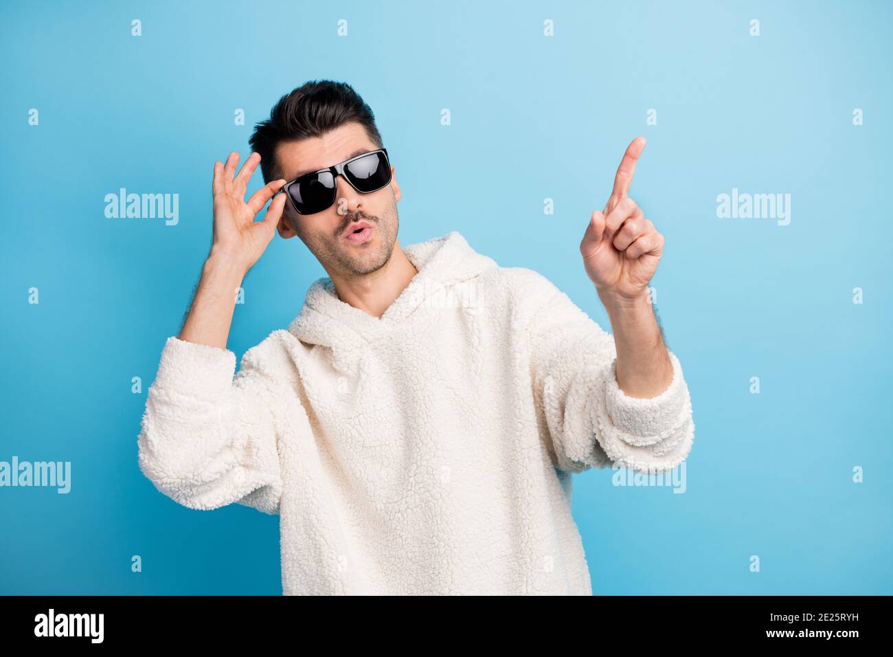 Ritratto fotografico di un ragazzo fresco con gli occhiali a contatto con le setole rivolti verso l'altro dito sullo spazio vuoto isolato su sfondo di colore blu pastello Foto Stock