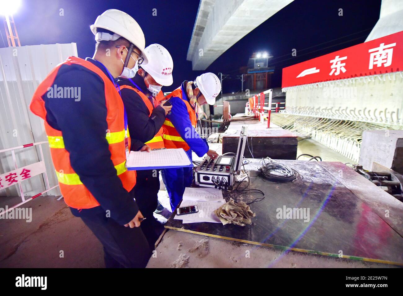 Fuzhou, la provincia cinese di Fujian. 12 gennaio 2021. I tecnici lavorano nel luogo di costruzione della rotazione di un'enorme trave per un grande ponte della ferrovia ad alta velocità Fuzhou-Xiamen a Qingkou città della contea di Minhou, la provincia del Fujian della Cina sudorientale, gennaio 12, 2021. La trave da 14,500 tonnellate, una parte del grande ponte di 896 metri, è stata girata con successo nella posizione di destinazione martedì. Credit: LIN Shanchuan/Xinhua/Alamy Live News Foto Stock