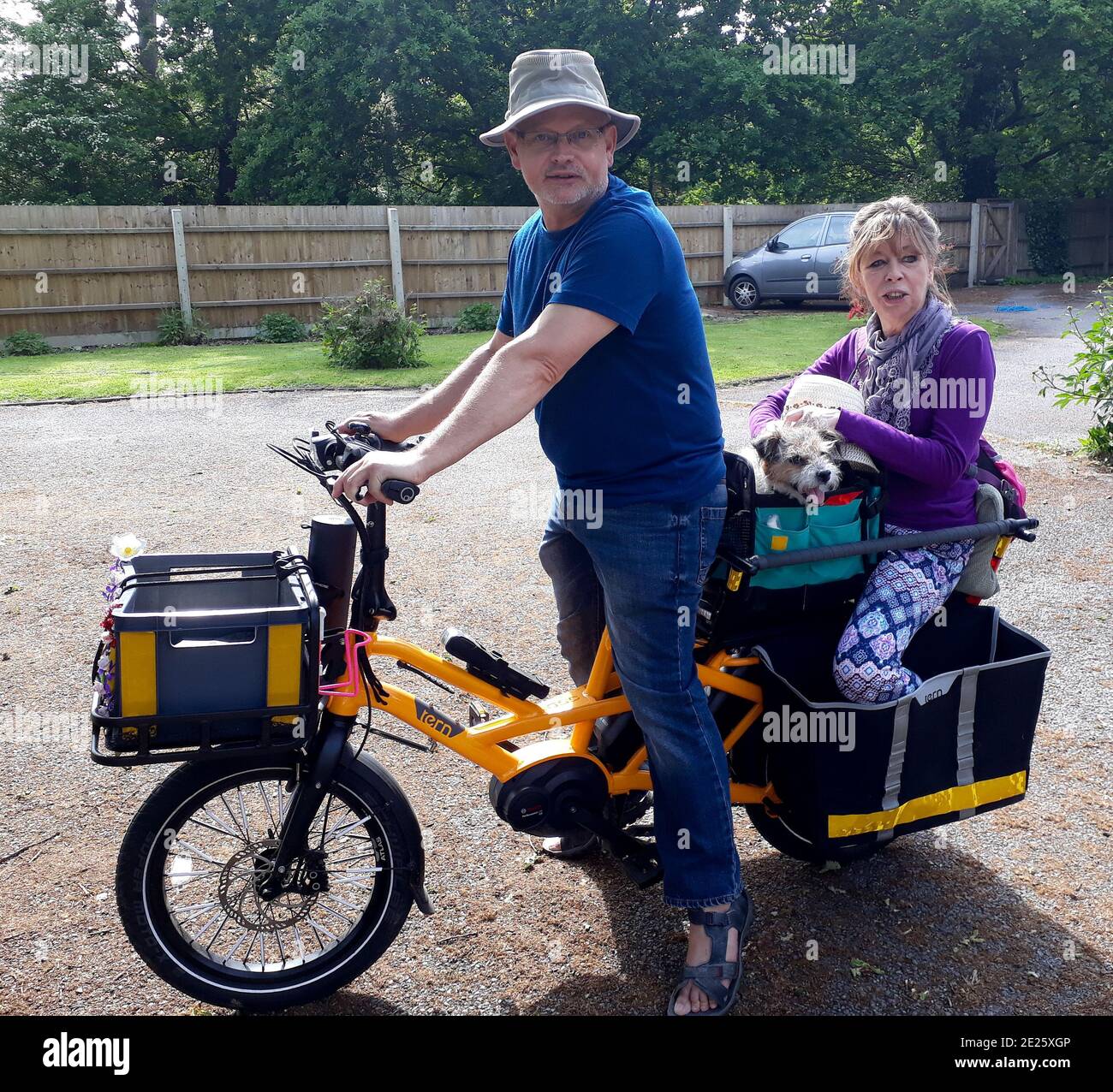 uomo, donna e cane piccolo su una bicicletta elettrica gialla carico Foto Stock