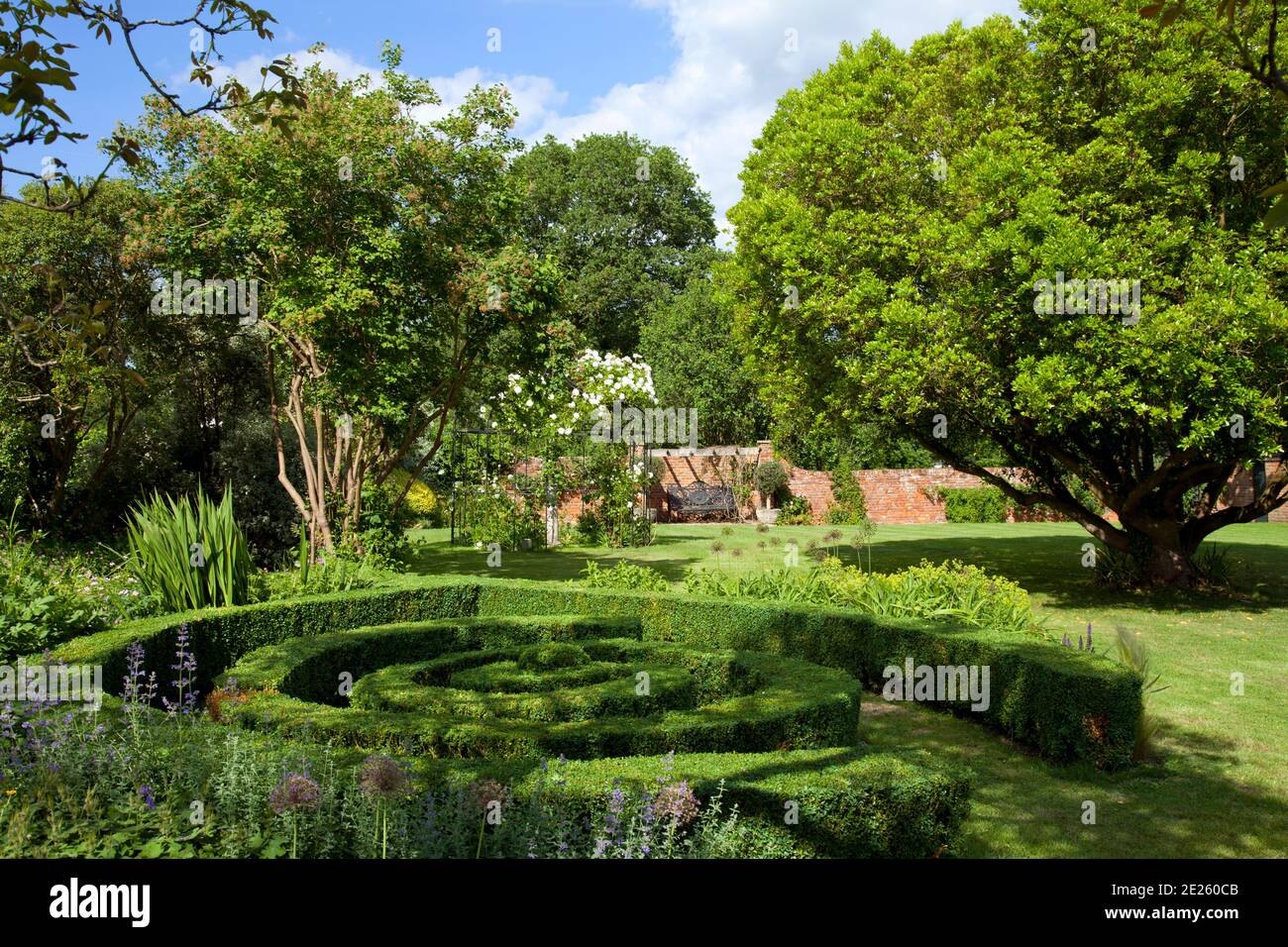 Giardino murato con labirinto come copertura di scatola, prato, letto di fiori e alberi maturi Foto Stock