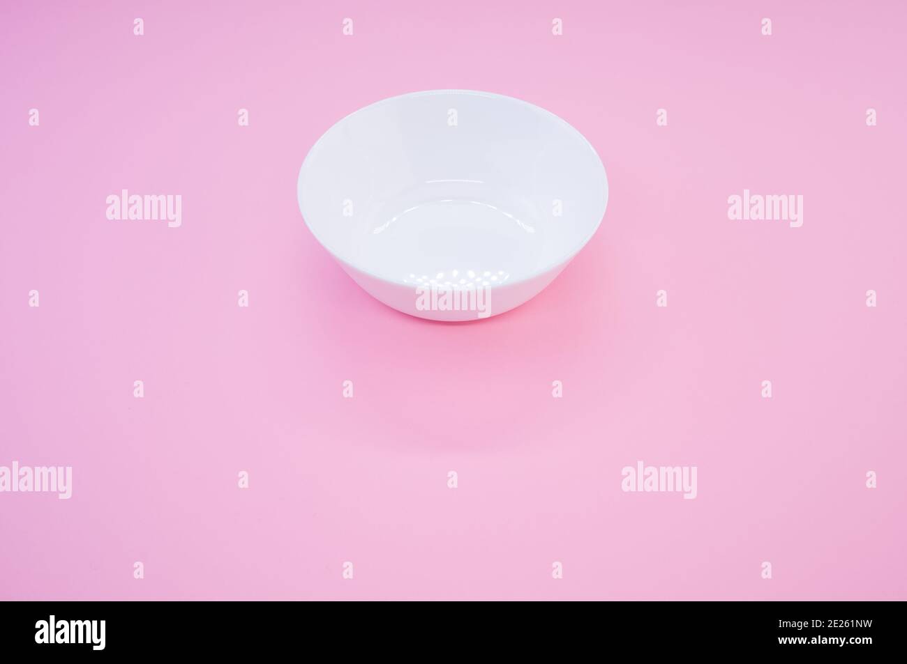 Immagine ad alta angolazione di un recipiente in vetro bianco vuoto su uno sfondo rosa Foto Stock