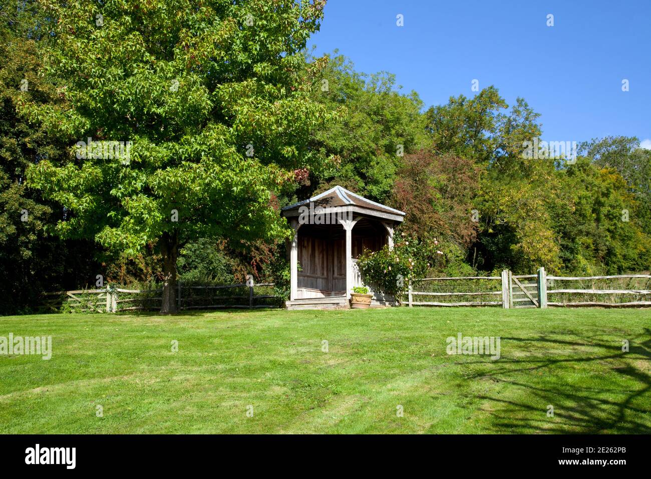 Aperto gazebo in legno casa estiva sul bordo del prato circondato da alberi Foto Stock