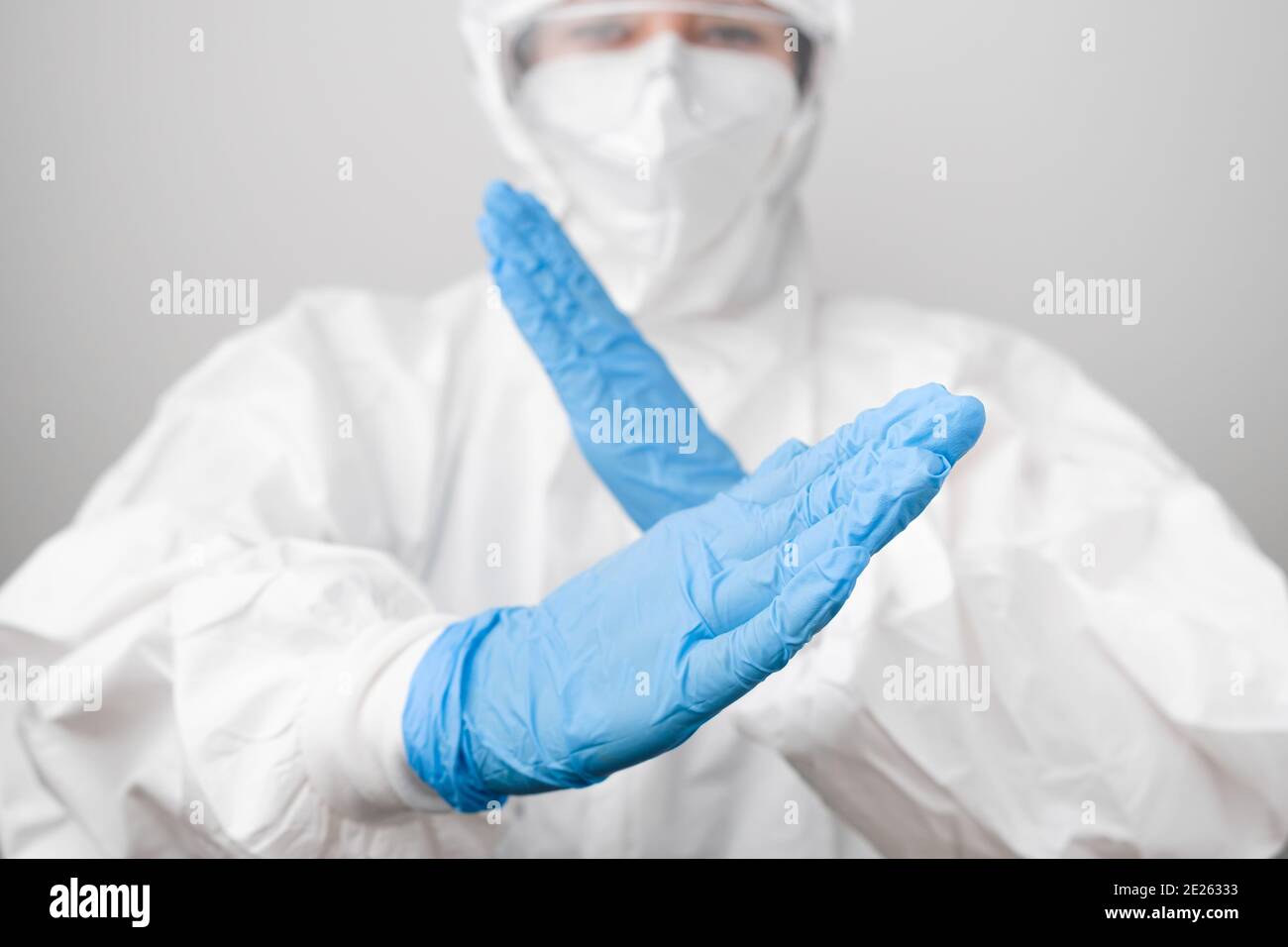 Medico in una tuta protettiva contro il rischio biologico e maschera protettiva contro il coronavirus, Sars-Cov-2, Covid-19 in guanti di gomma blu. Foto Stock