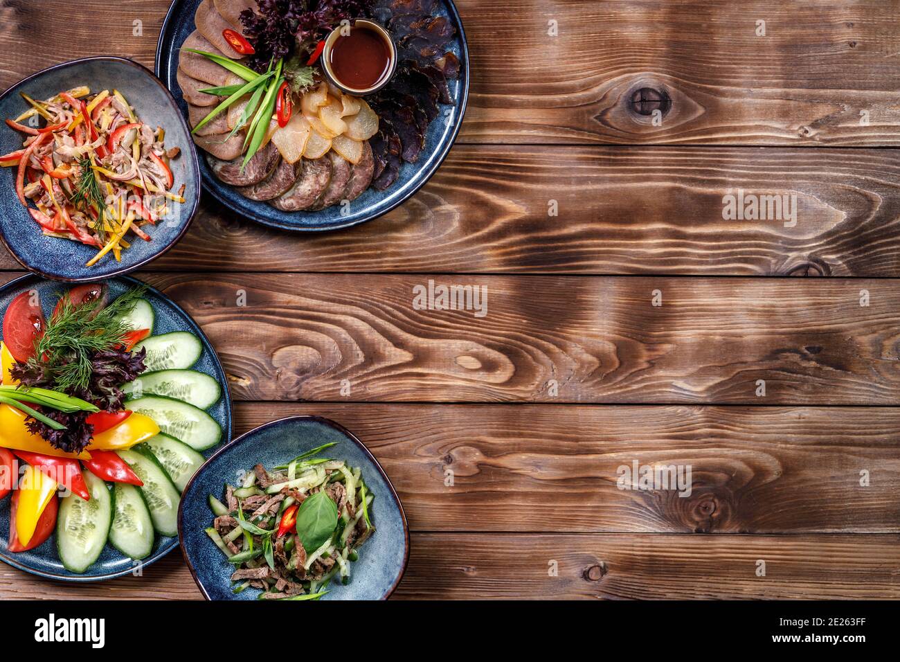 Disposizione piatta di vari piatti con verdure a fette, tagli di carne, insalate su fondo di legno marrone. Spazio di copia. Foto Stock