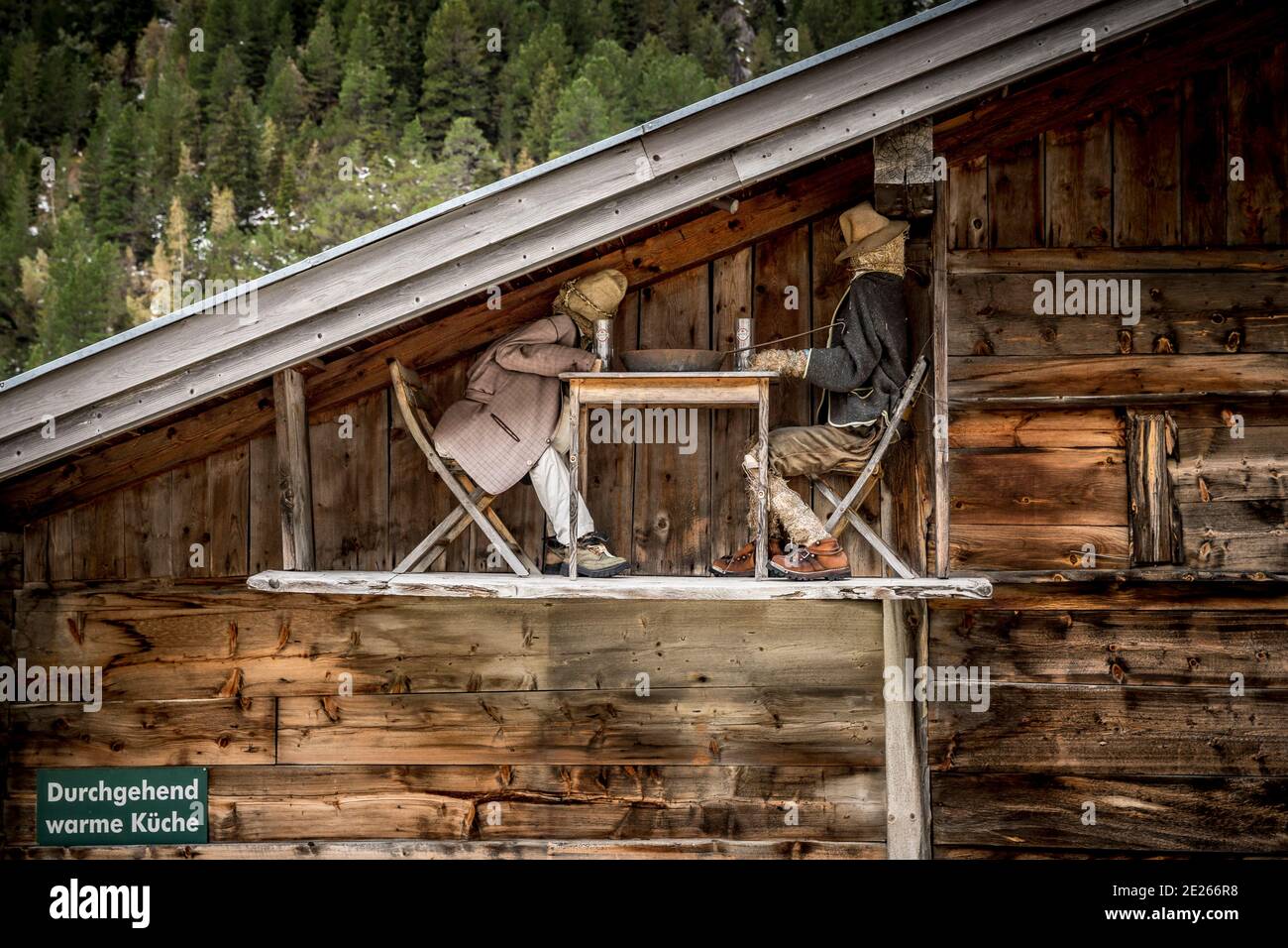 Scena divertente su fienile alpino in legno che mostra due figure di paglia bere birra ad un tavolo, Hohe Tauern National Park, Carinzia / Kärnten, Austria Foto Stock