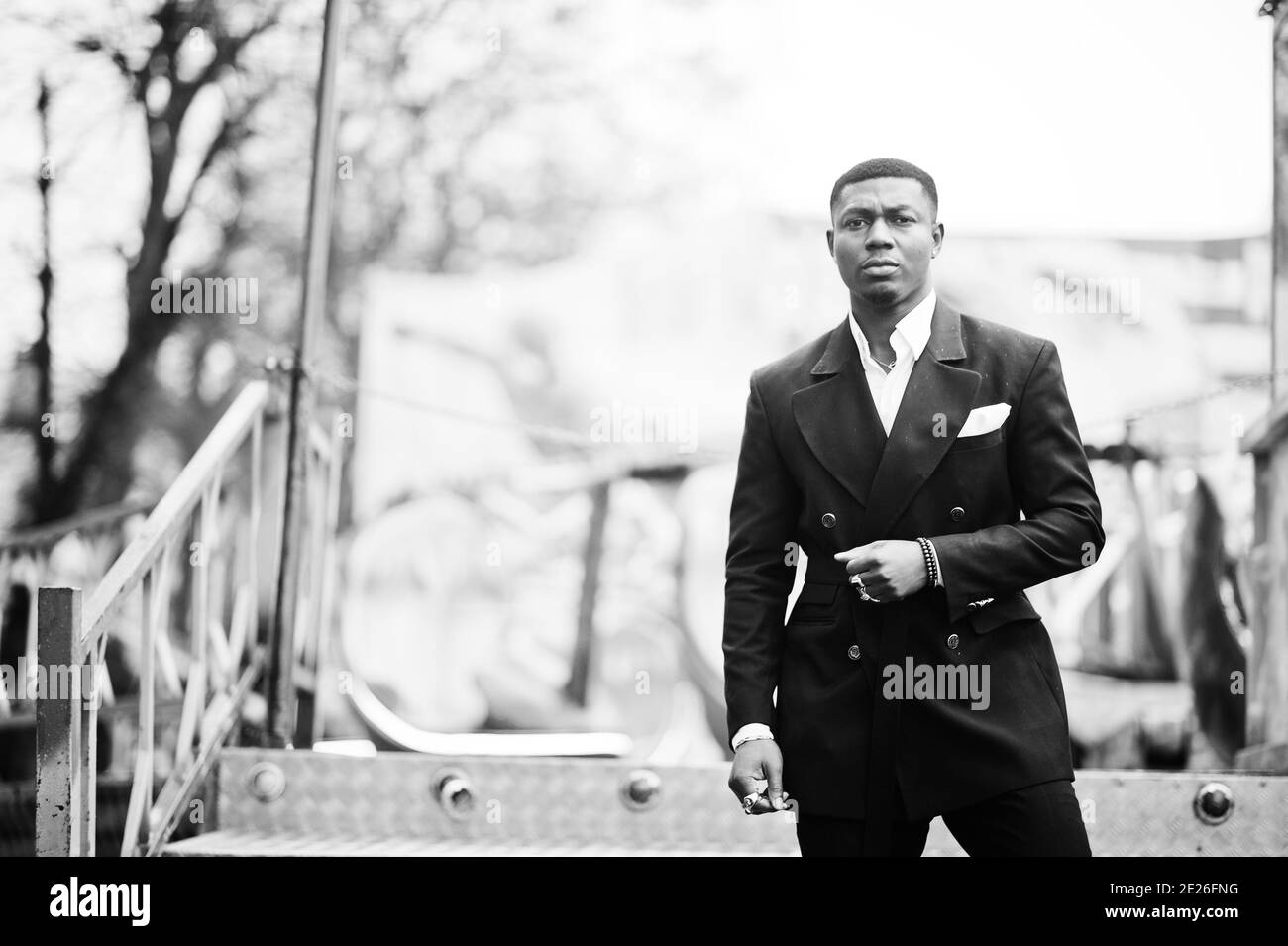 Ritratto di giovane e bell'uomo d'affari afro-americano in tuta posa sfondo giostra attrazioni. Foto Stock