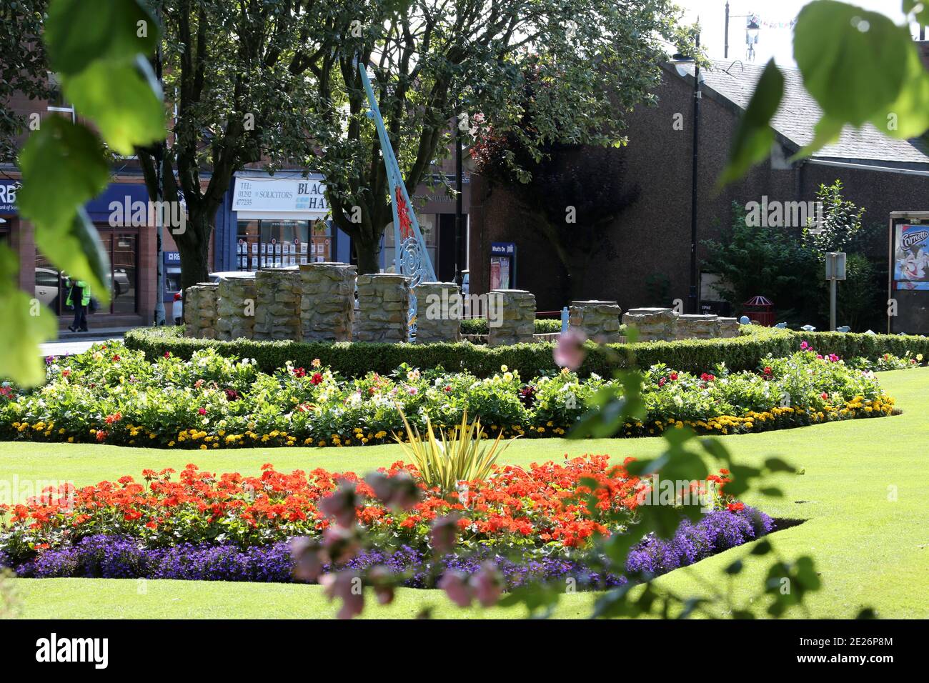 Prestwick Cross, Prestwick , Ayrshire, Scozia. REGNO UNITO. L'insolita meridiana mostra dalle 4:00 alle 20:00 in orario. I segnaora sono su colonne costruite in pietra con motivi che denotano gli interessi locali. Grande gnomone trafitto con elaborati simboli di sole, luna, stelle e zodiaco. La piastra è di concre &tegole, facendo una mappa approssimativa del Firth di Clyde, con l'Isola di Arran, e alcune strade sulla terraferma. La meridiana è stata concepita e progettata da studenti d'Arte della Prestwick Academy con l'assistenza di membri del Dipartimento d'Arte, che hanno lavorato in collaborazione con l'artista Elspeh Bennie di Balfron. Foto Stock