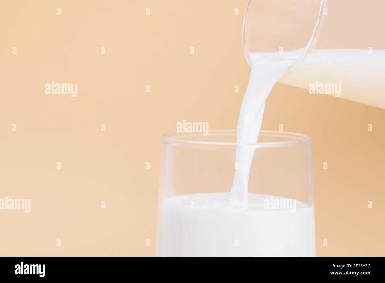 Closeup ha sparato o una caraffa e un bicchiere di latte da uno sfondo arancione Foto Stock
