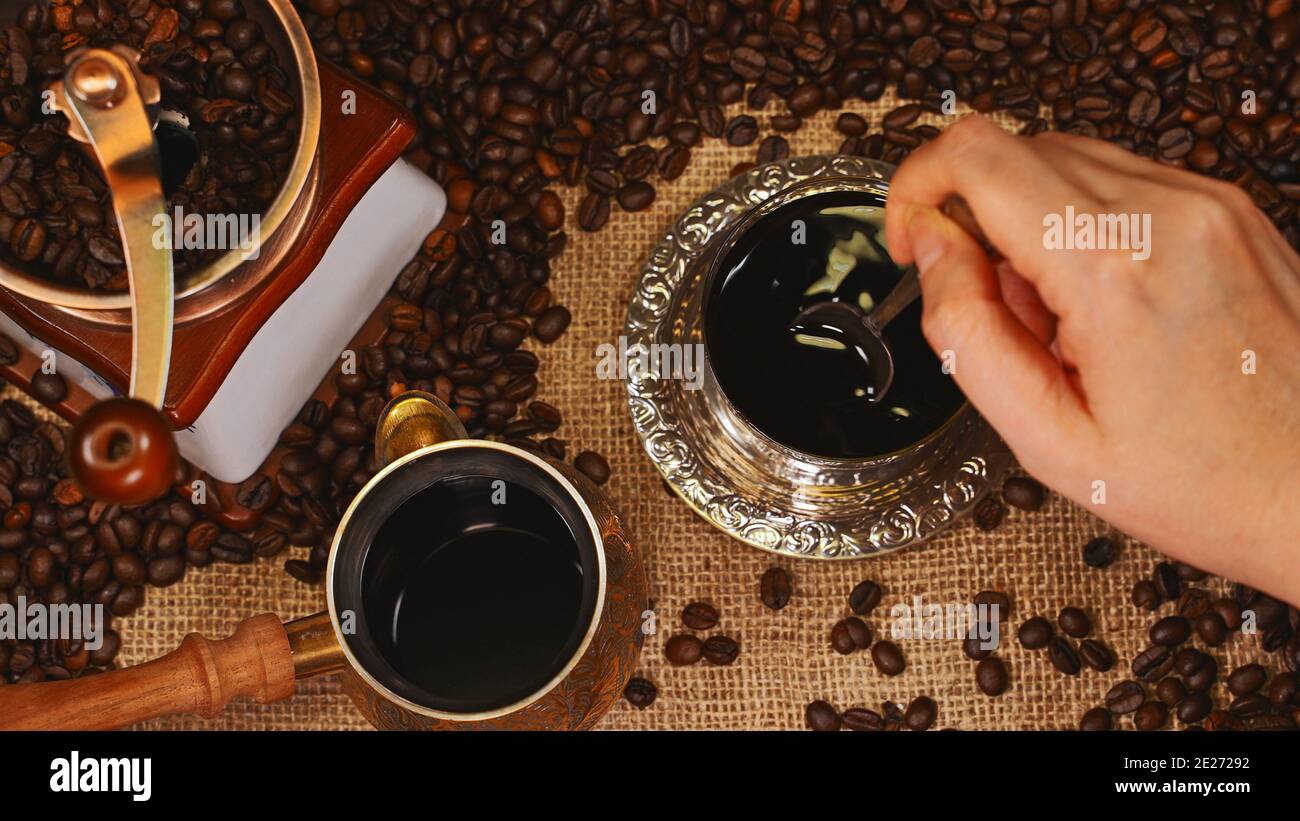Mano donna che mescola il caffè in tazza. Foto Stock