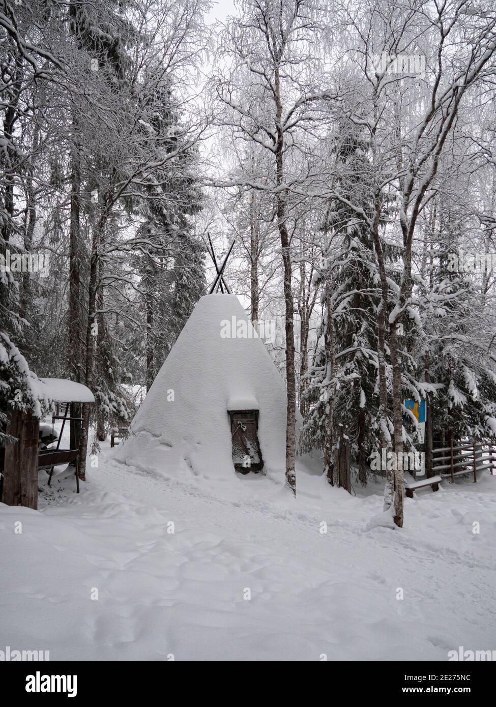 Casa di legno nella foresta invernale. Lapponia. Casa nella neve e falò. Foto Stock