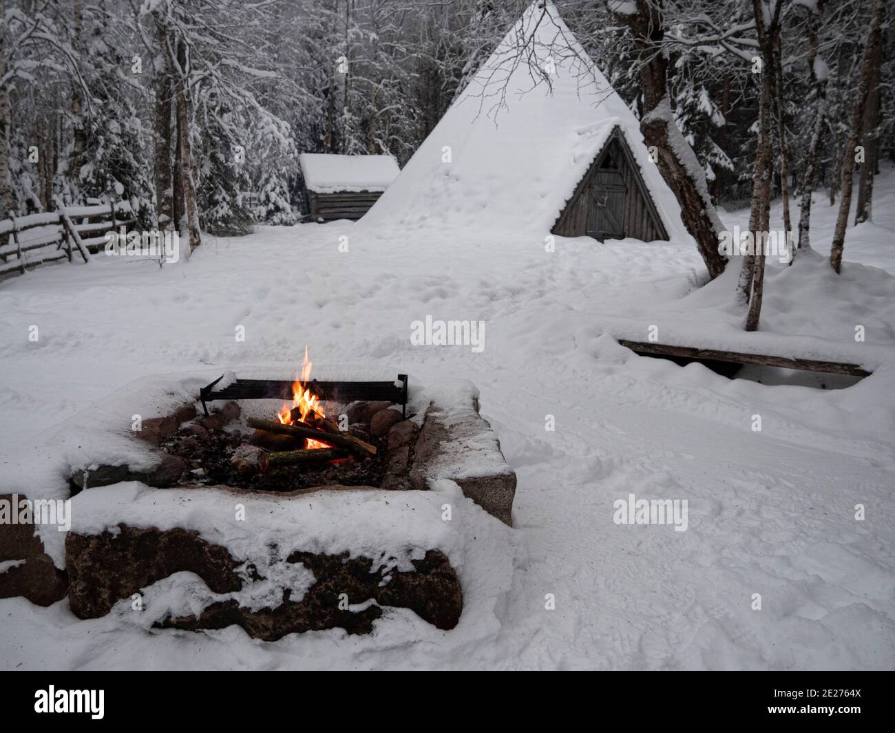 Casa di legno nella foresta invernale. Lapponia. Casa nella neve e falò. Foto Stock
