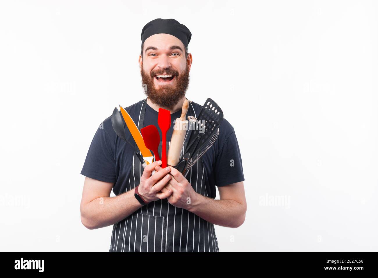Foto di un uomo Chef con bearded stupito che tiene in mano gli utensili. Foto Stock