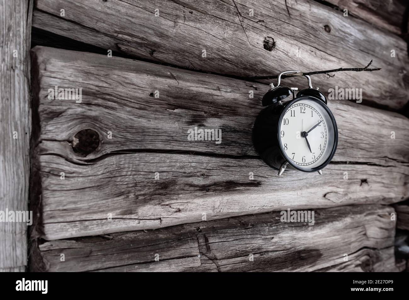Una campana appesa su un sottile bastone di legno bloccato una vecchia casa di tronchi Foto Stock