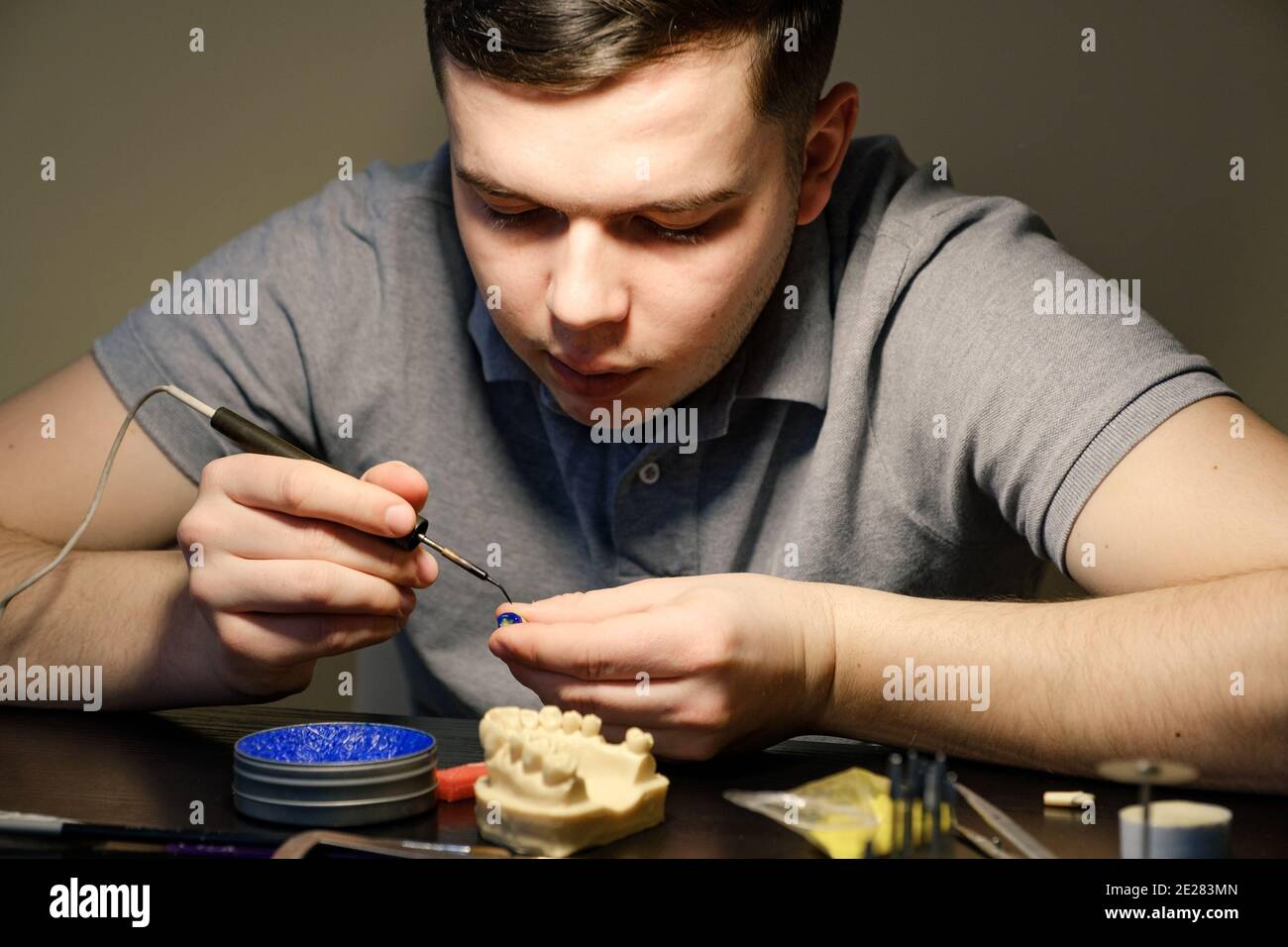Tecnico dentale modellando le corone dei denti con cera calda. Luogo di lavoro di un tecnico odontoiatrico Foto Stock