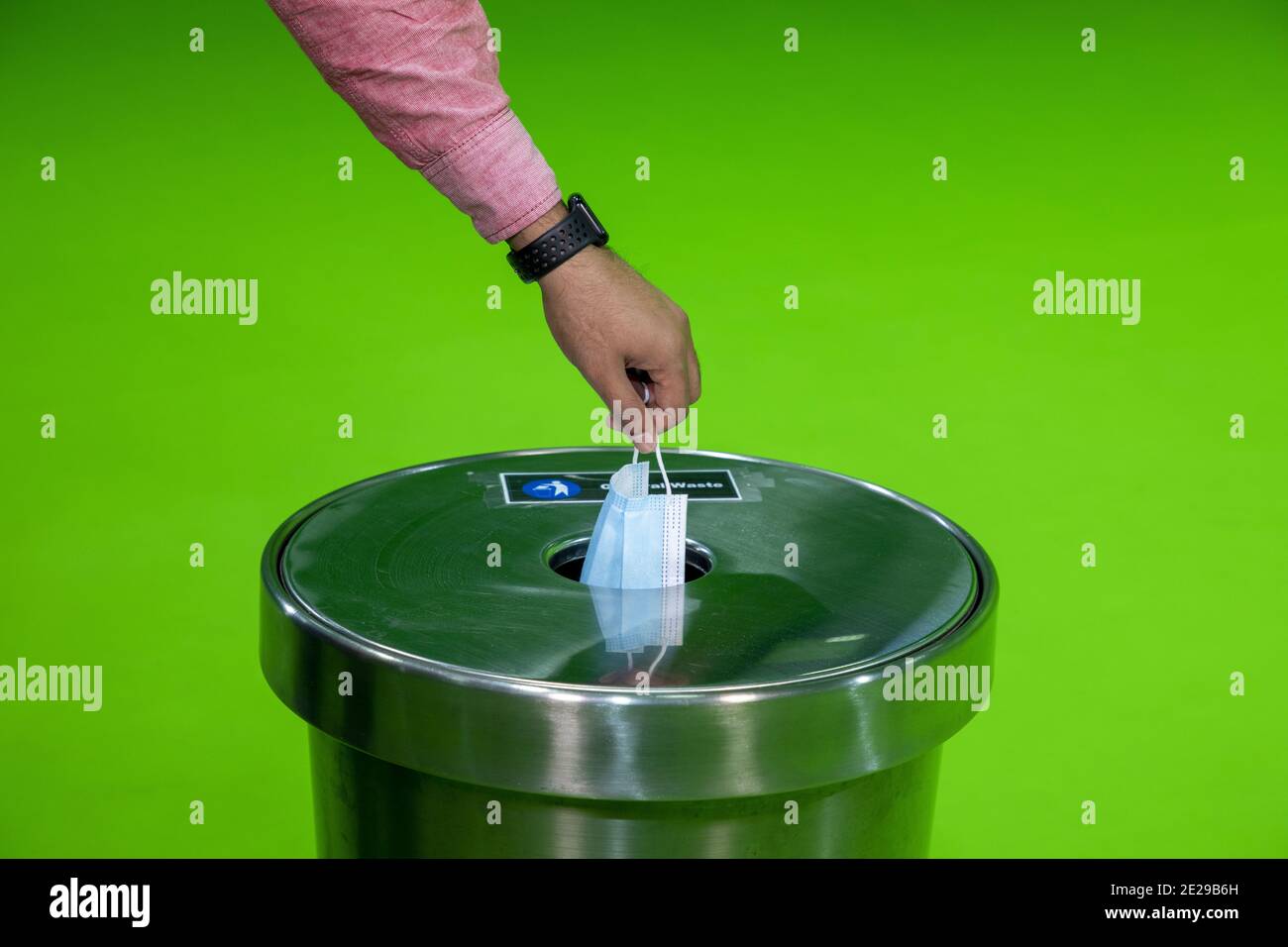 Un uomo toglie la maschera medica protettiva e lo scarico in cestino Foto Stock