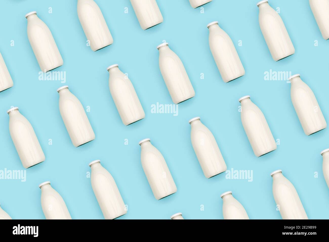 Modello realizzato con bottiglia di latte in vetro trasparente su fondo blu. Vista Flat Lay Top. Foto Stock