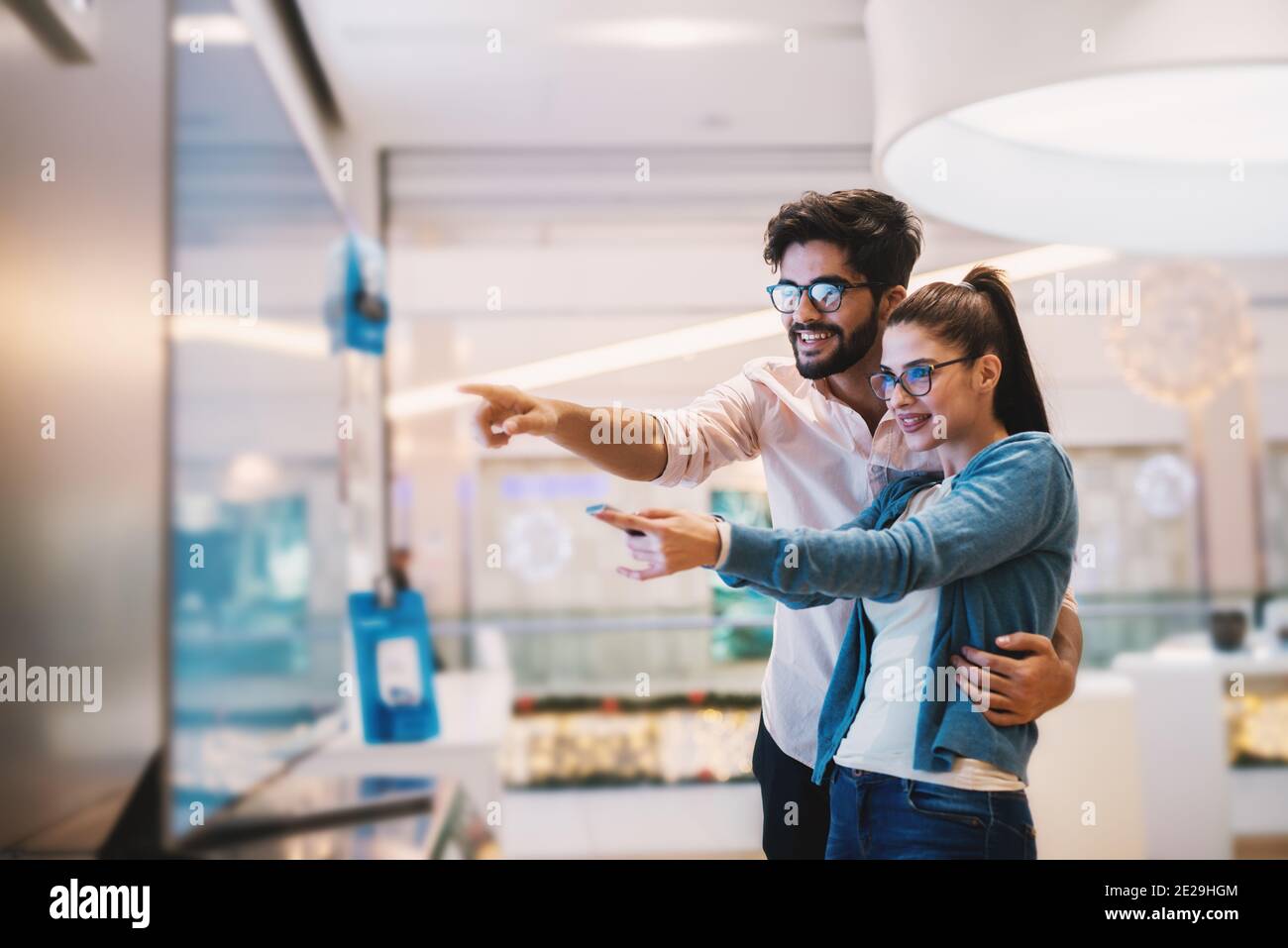 Giovane coppia entusiasta che guarda il grande schermo TV per loro nuovo negozio home.at tech Foto Stock