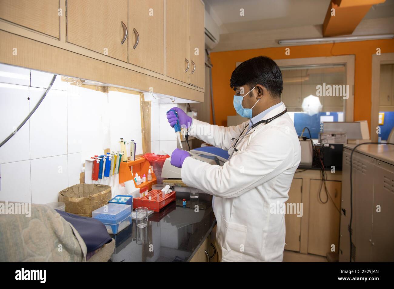 Medico indiano scienziato medico che indossa maschera chirurgica faccia fare chimica o ricerca di droga in laboratorio clinico per vaccino virus covid, assistenza sanitaria Foto Stock